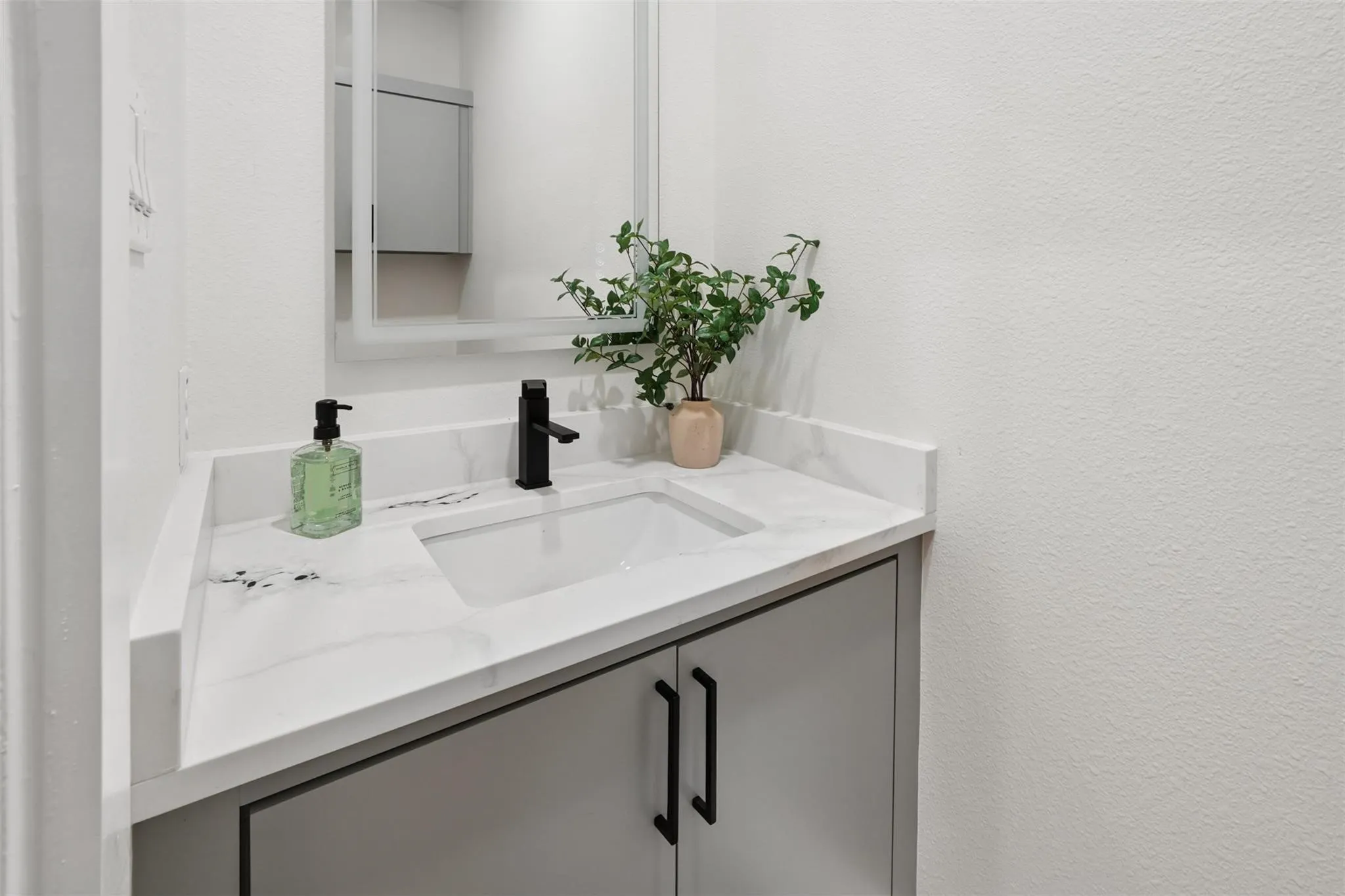 White countertop with integrated rectangular sink and black matte faucet