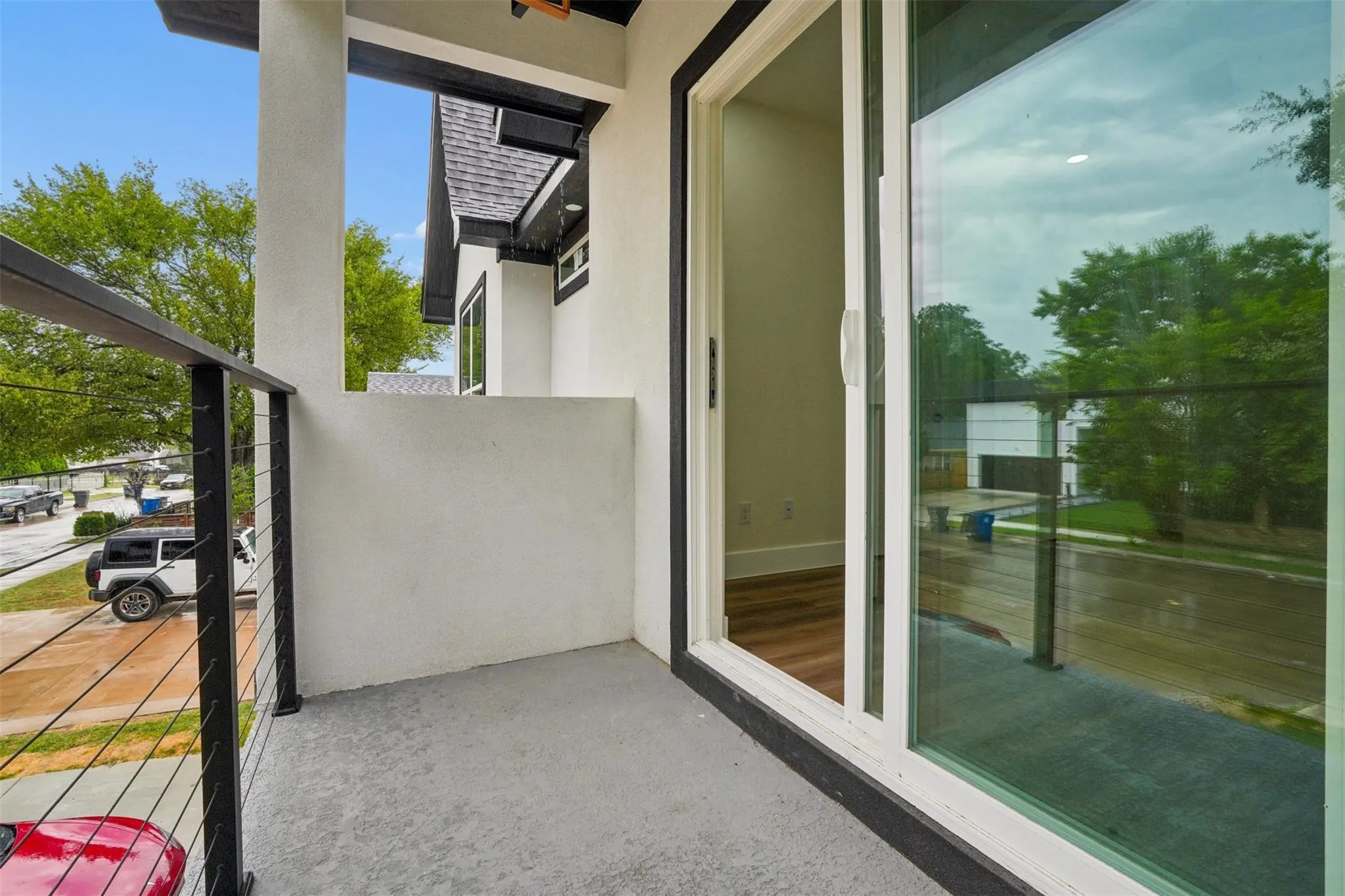 Balcony featuring a concrete surface, black cable railing, and a sliding glass door