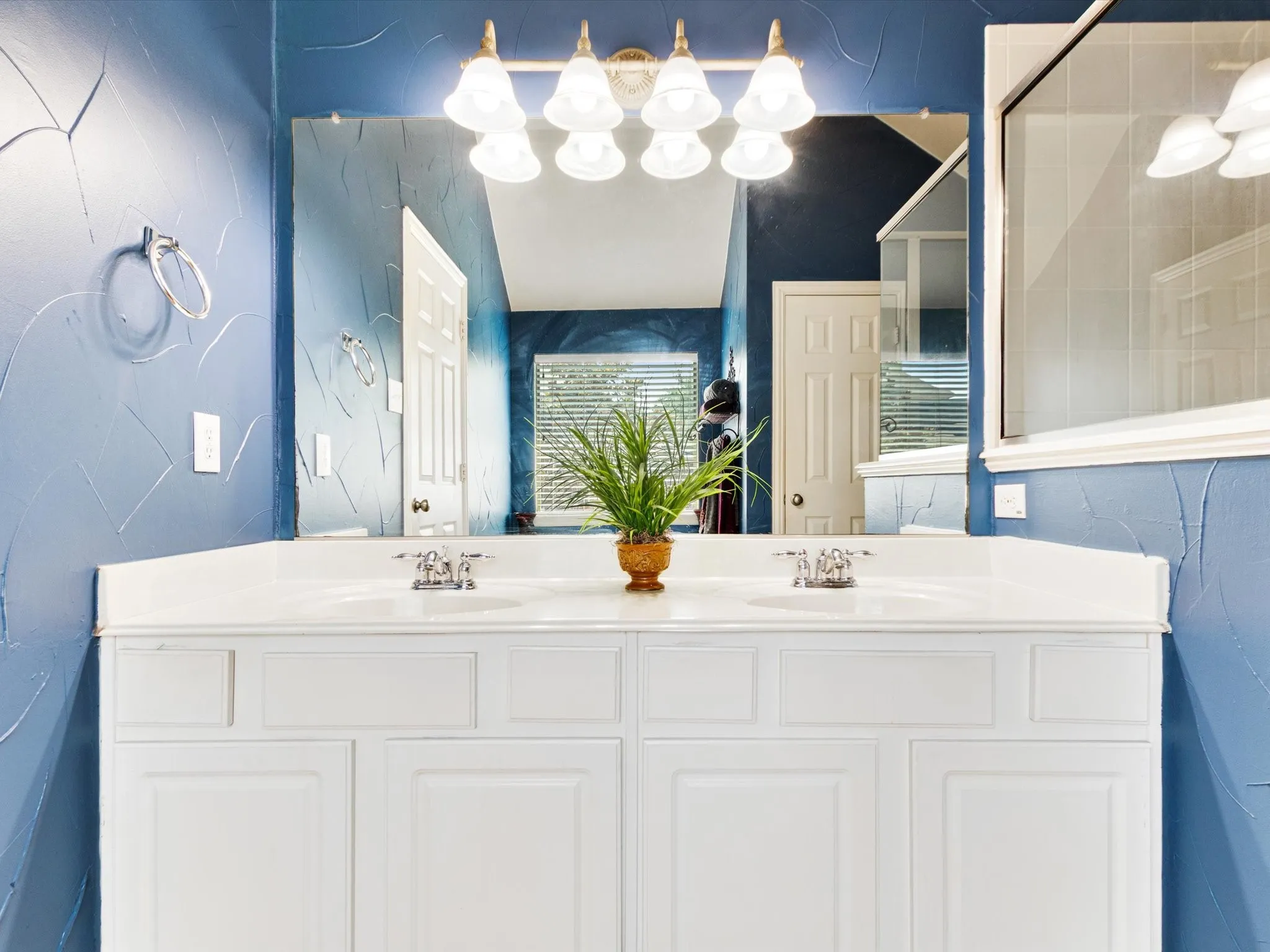Dual vanity with integrated sinks, white cabinetry, and wall-mounted light fixture