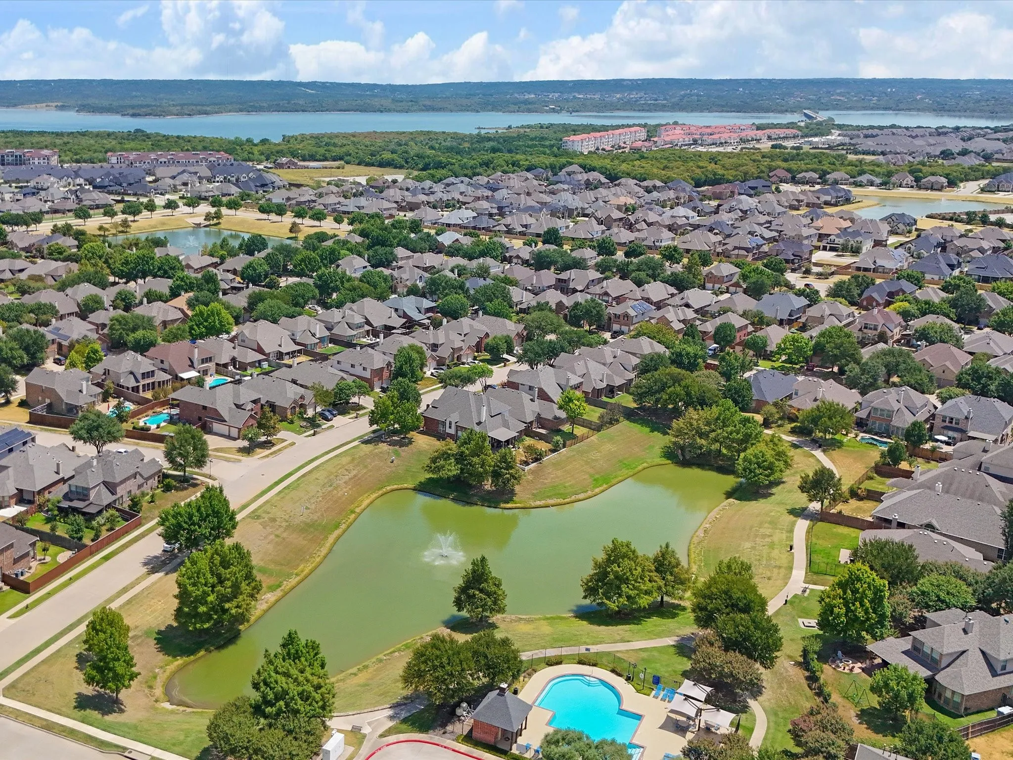 Community setting with a central pond, surrounding walking paths, and a swimming pool