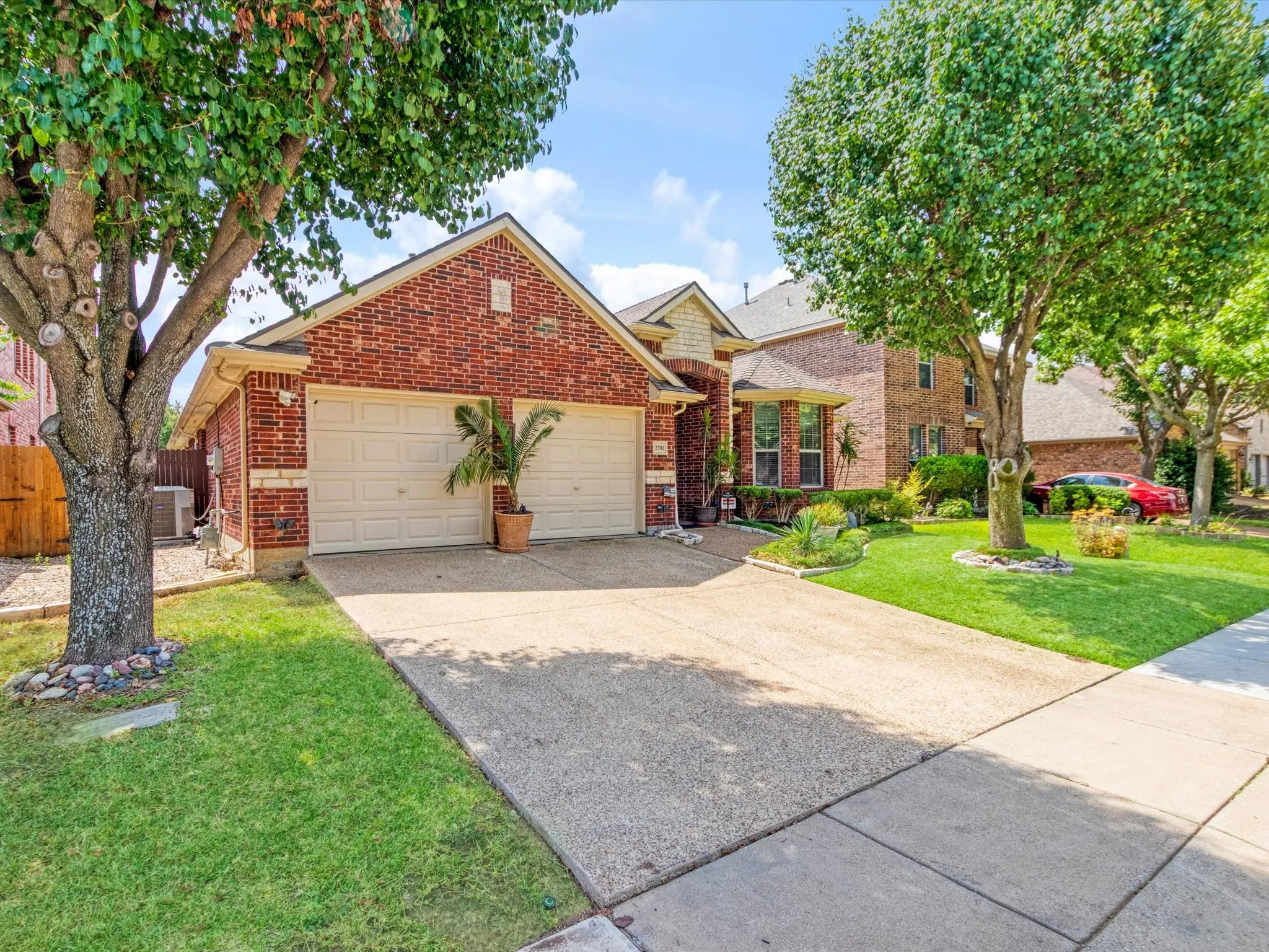 Brick exterior with a two-car garage, concrete driveway, and front lawn