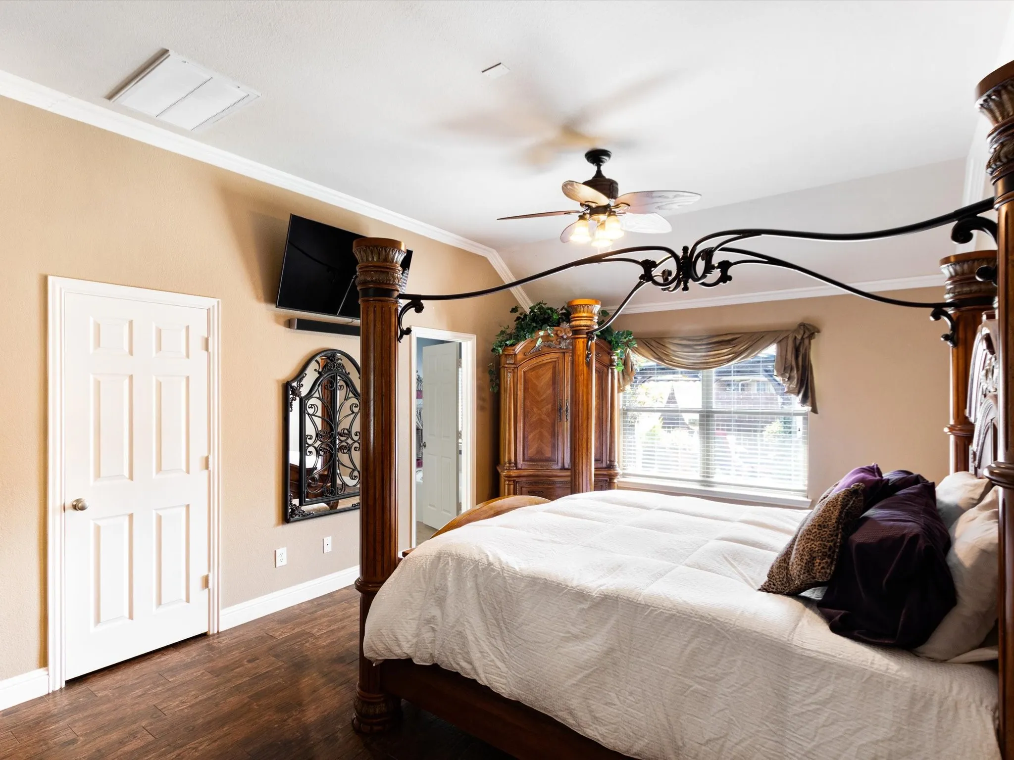 Wood-finish flooring, crown molding, ceiling fan, and six-panel interior door