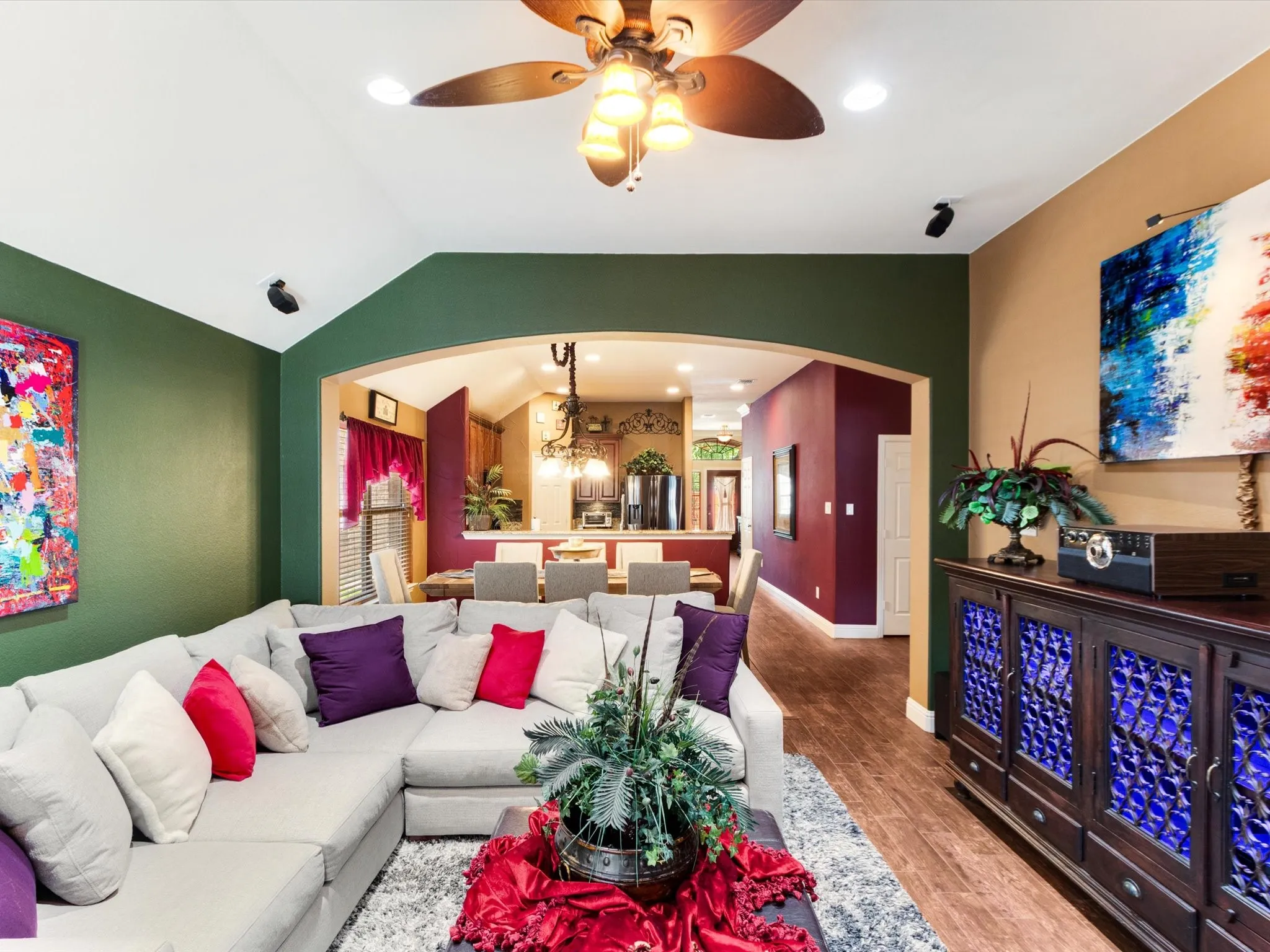 Vaulted ceiling, ceiling fan with integrated lighting, recessed lighting, arched doorway, and wood-finish flooring