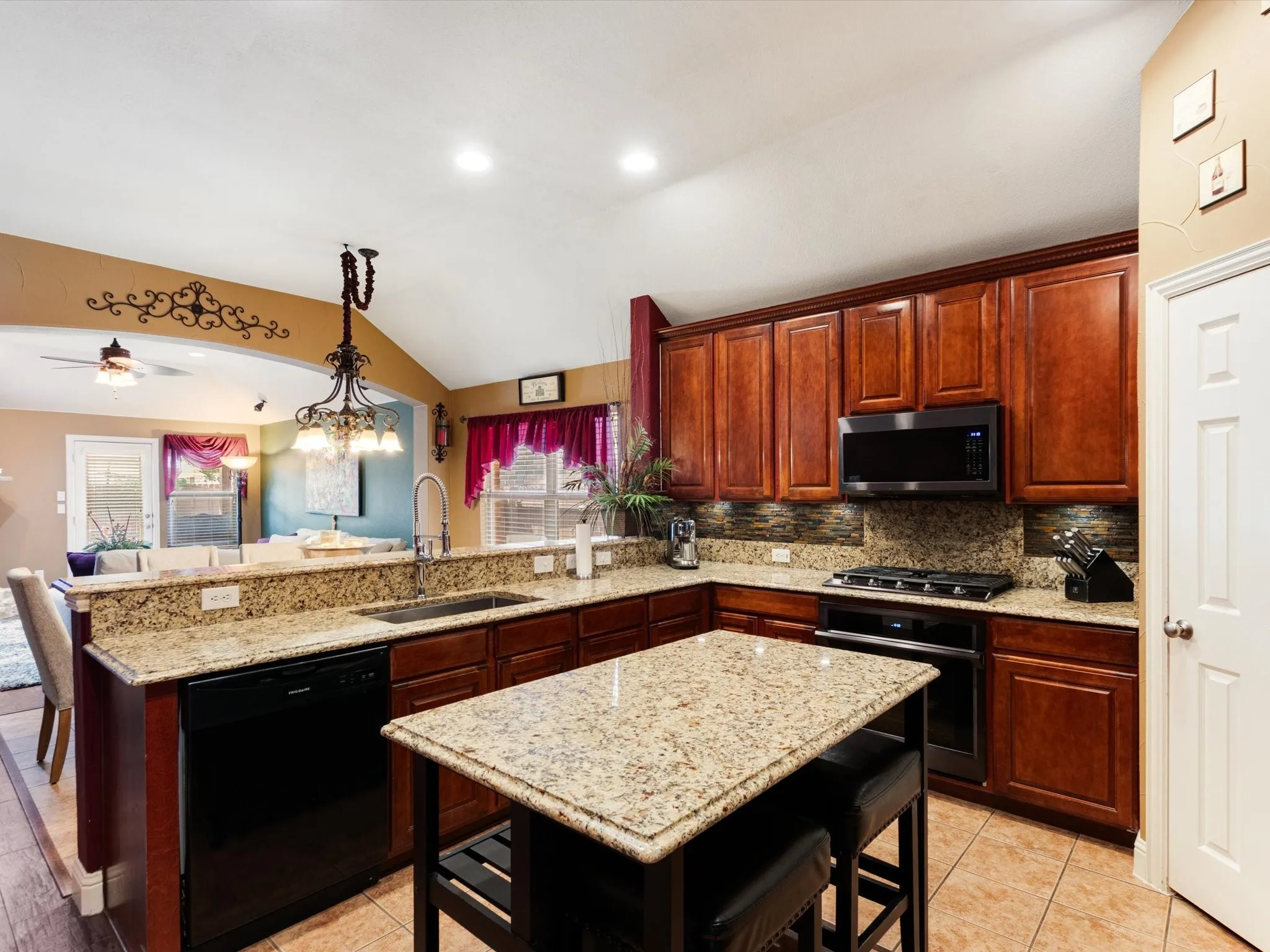 Kitchen featuring wood cabinetry, granite countertops, tile flooring, a built-in microwave, and a gas range