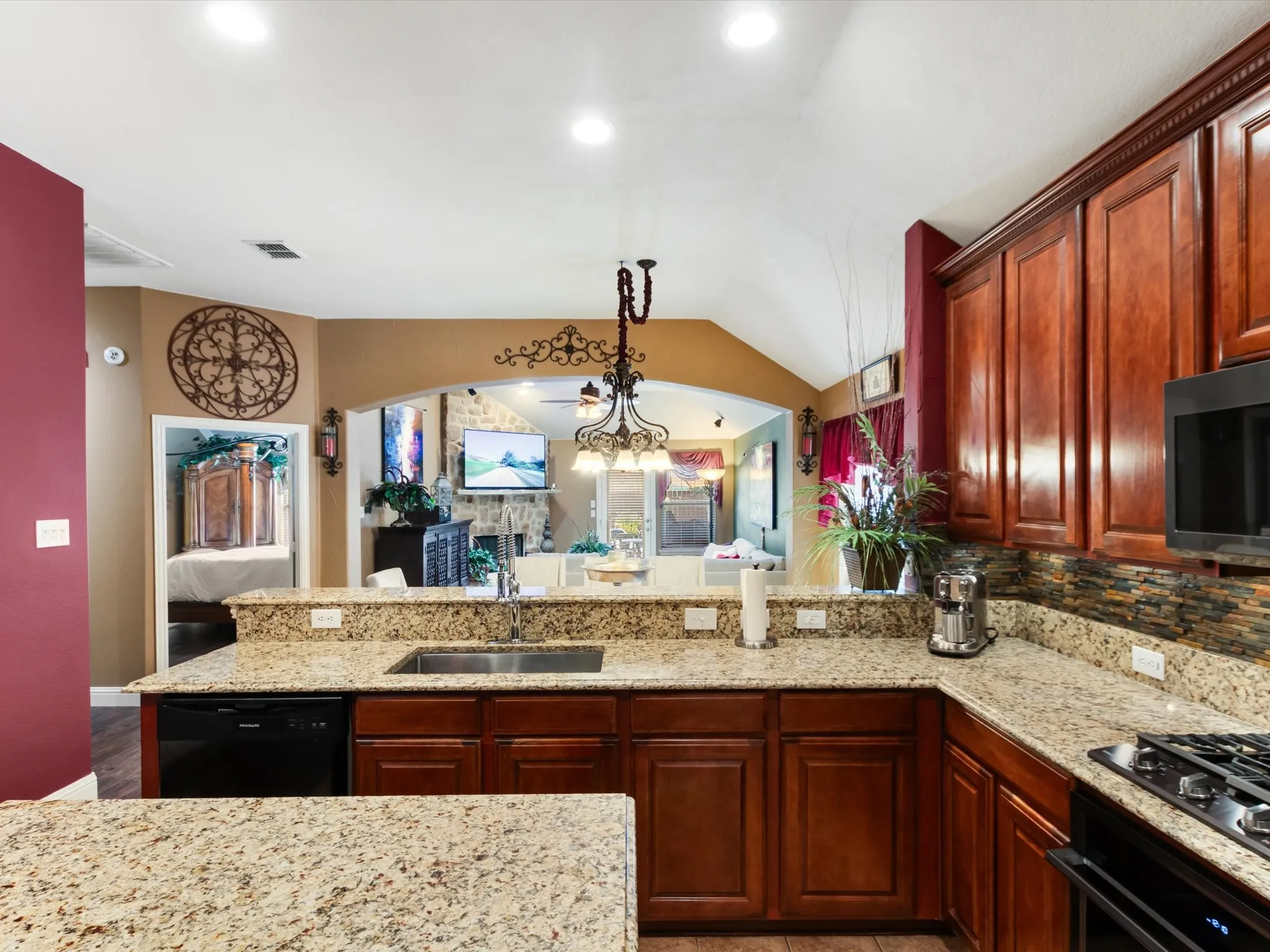 Kitchen featuring granite countertops, wood cabinetry, stainless steel sink, and tile backsplash