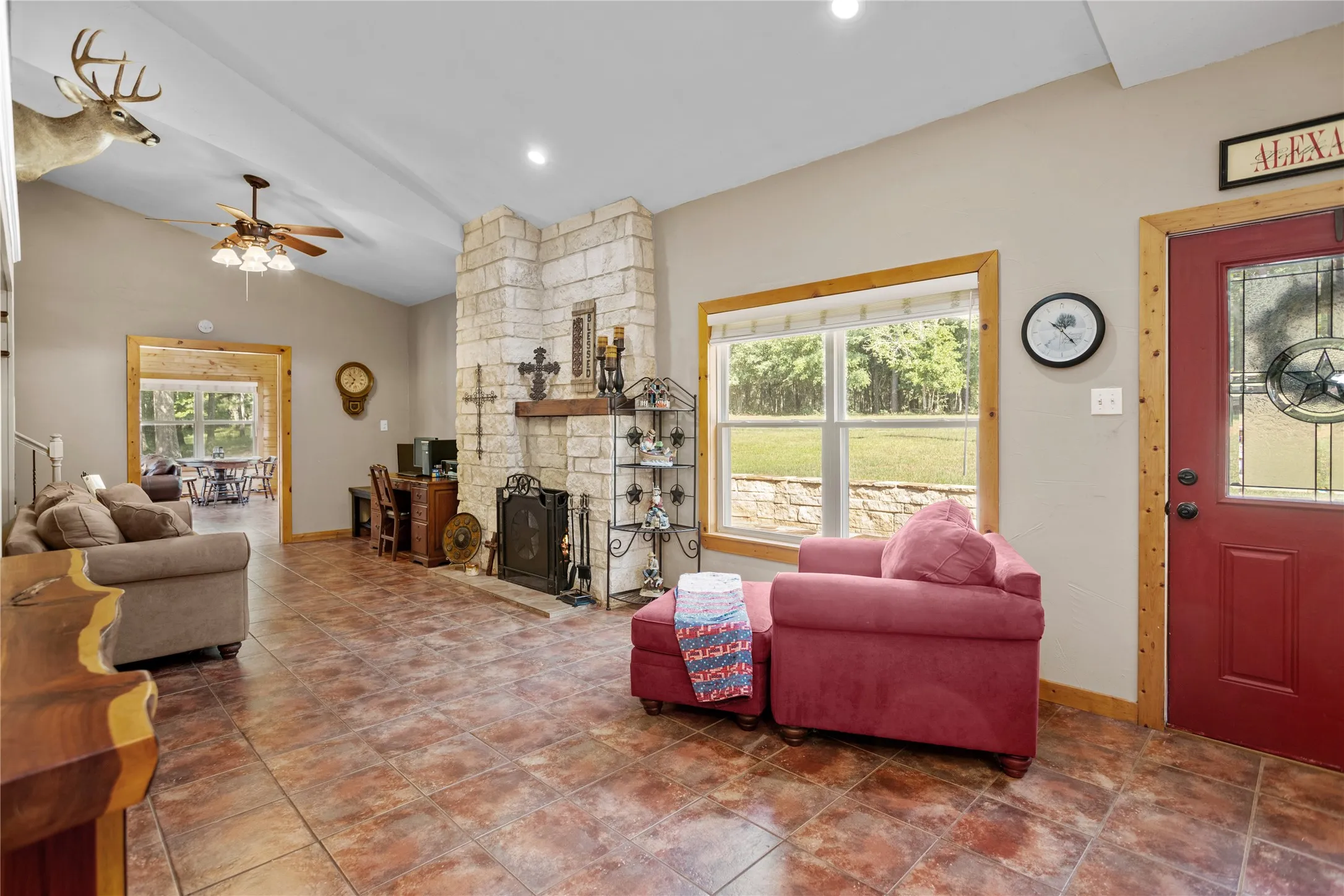Living area featuring vaulted ceiling, ceiling fan, and a stone fireplace