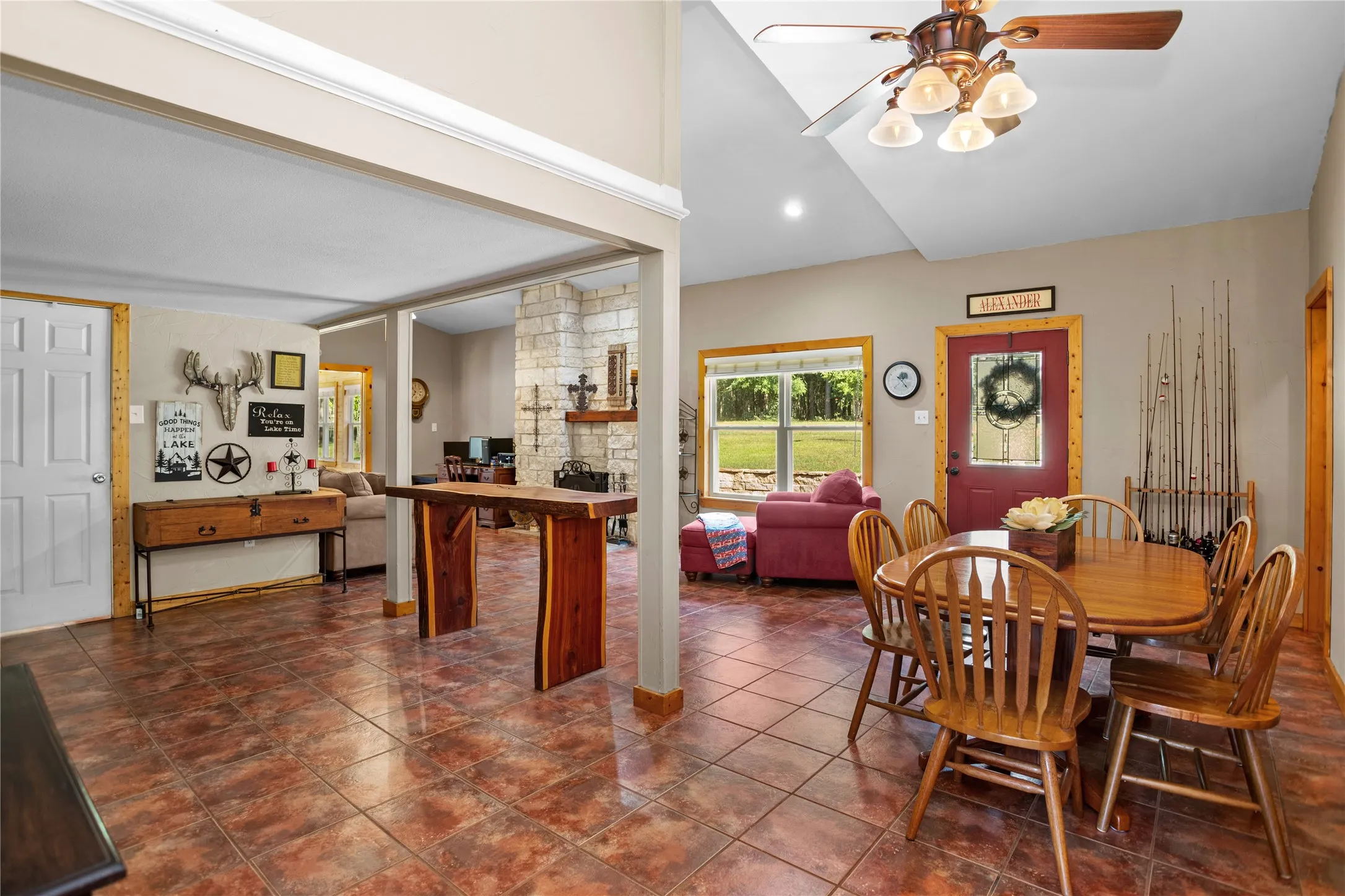 Dining area featuring ceiling fan, lofted ceiling, recessed lighting, a stone fireplace, and tile flooring