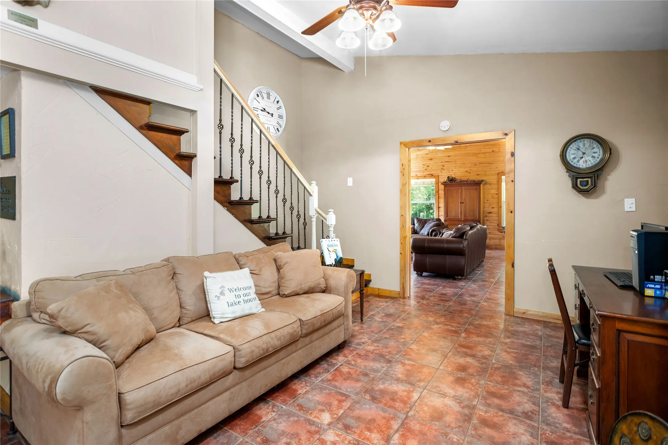 Tiled living room with stairway and a ceiling fan
