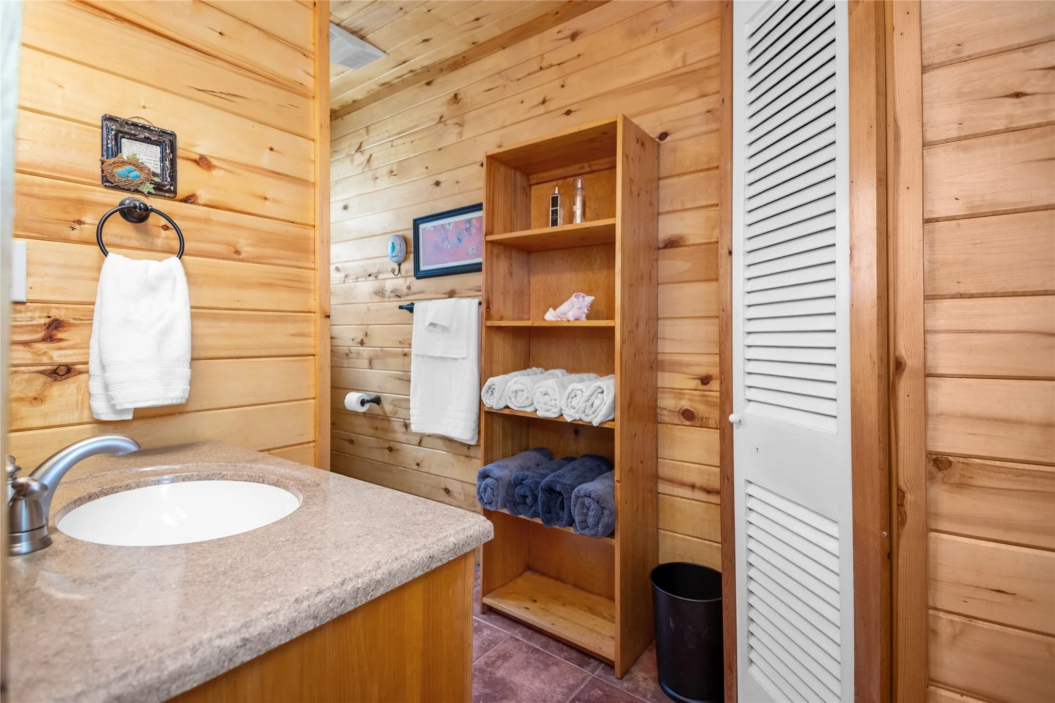 Bathroom with wood walls, vanity, and tile floors