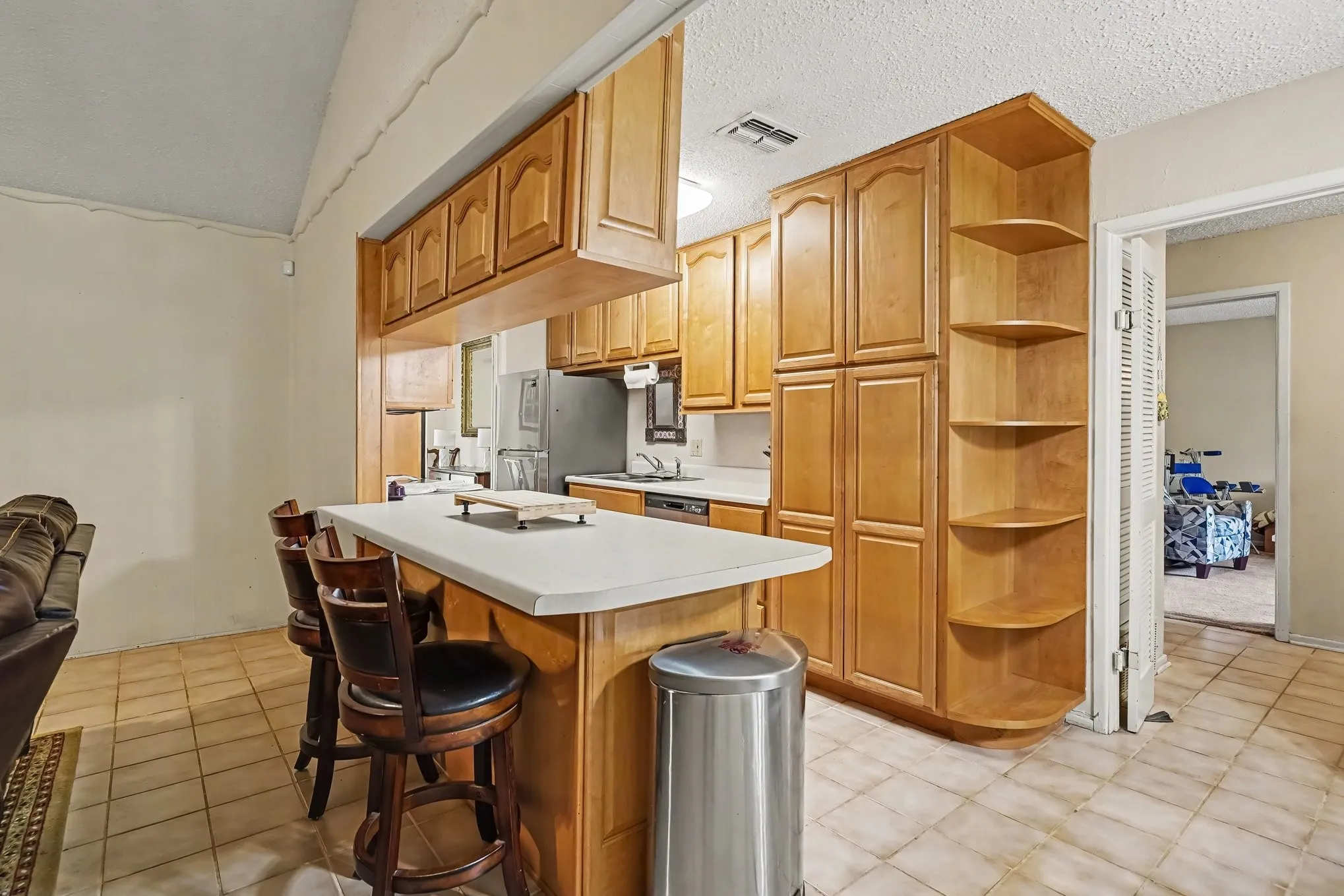 Kitchen featuring wood-finish cabinetry, solid surface countertops, a built-in breakfast bar, and tile flooring