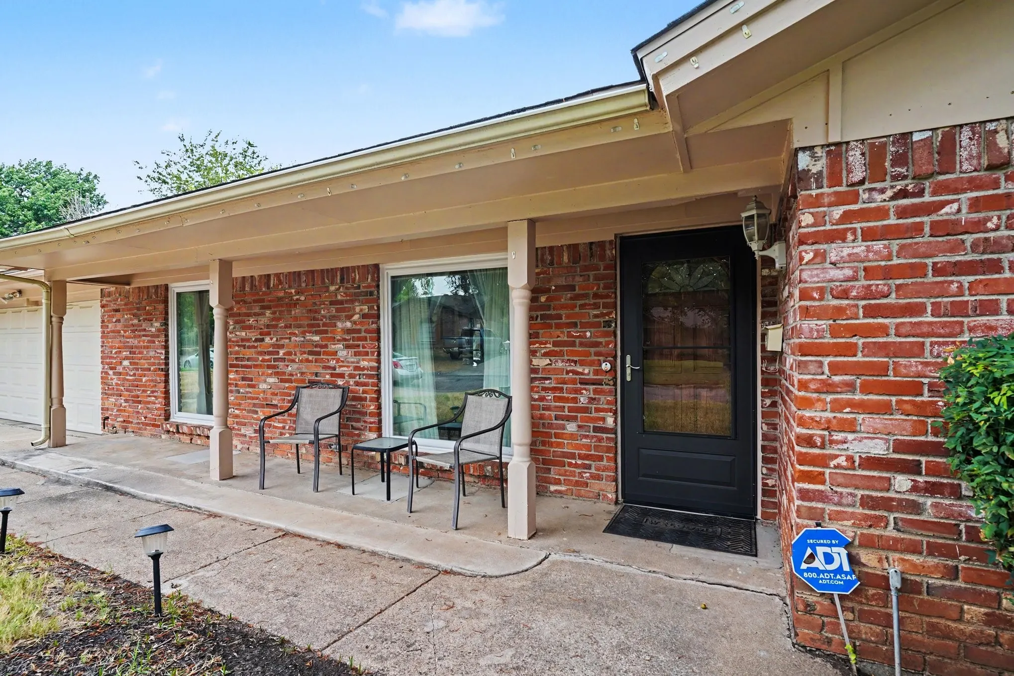 Brick exterior with covered entry, large windows, and an opaque panel front door