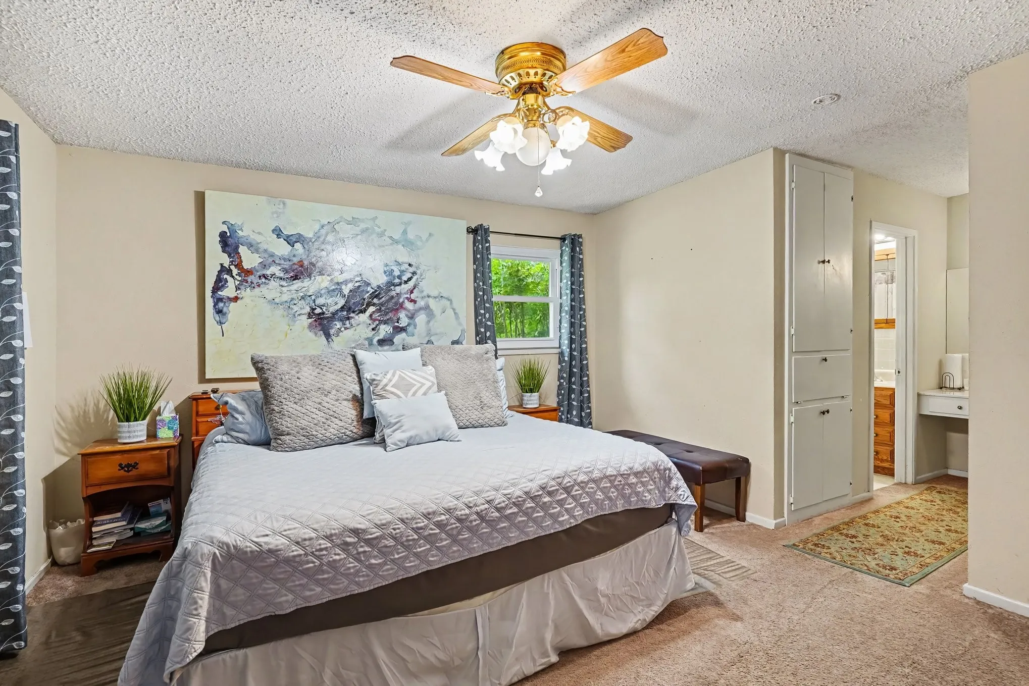 Textured ceiling with a ceiling fan, window with natural lighting, and built-in storage cabinetry