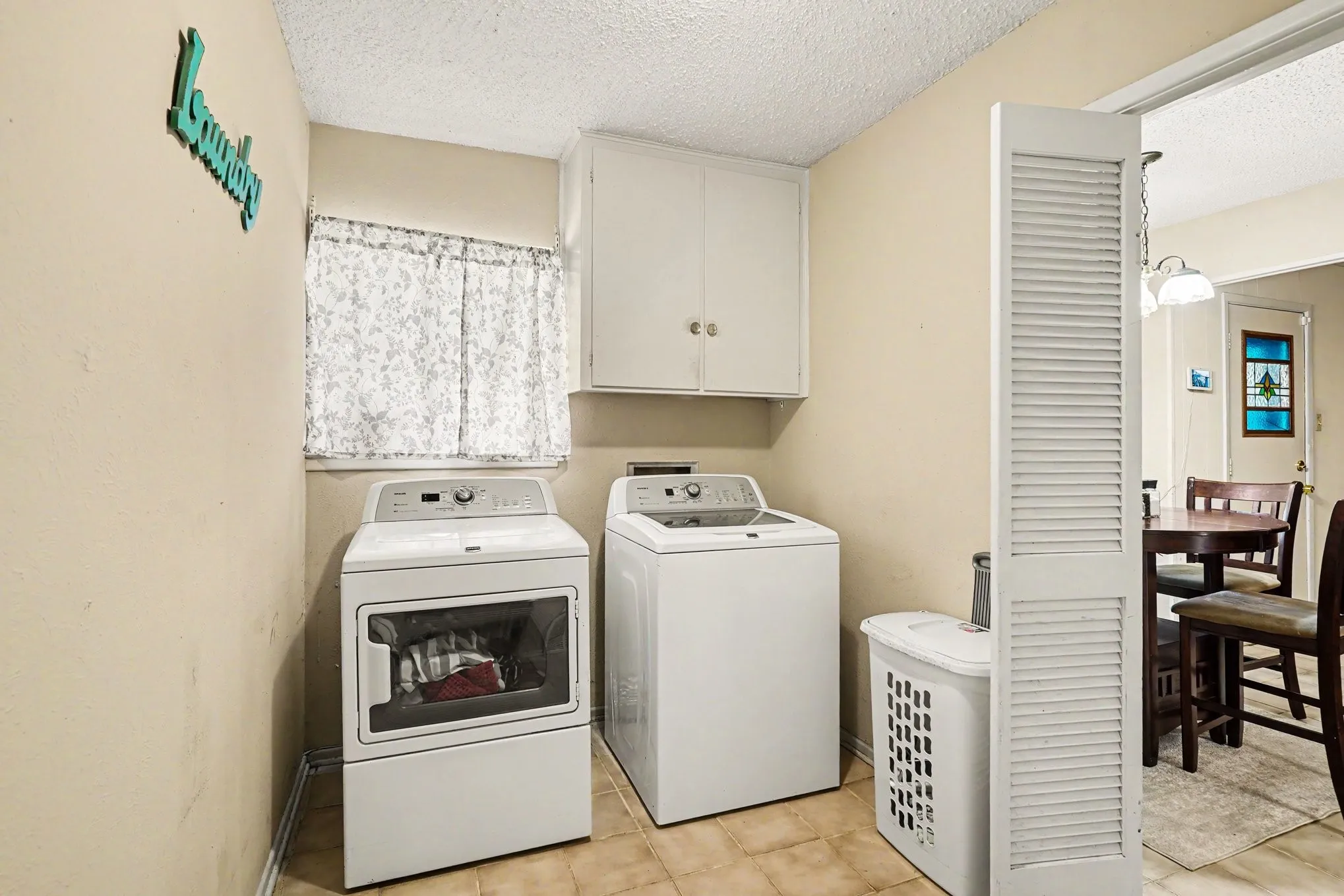 Laundry area with tile flooring and upper cabinetry