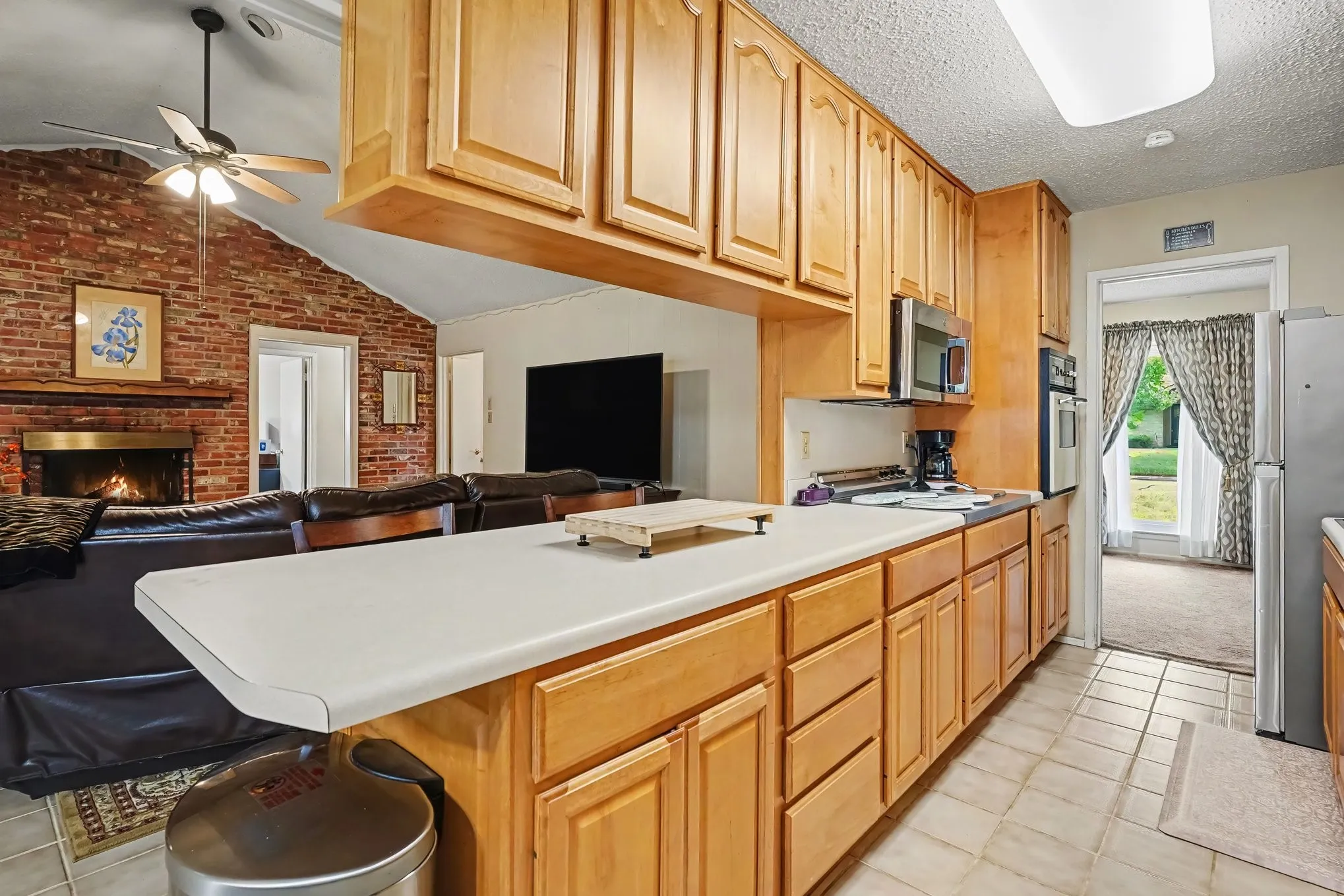 Kitchen with light wood-finish cabinetry, light-toned countertops, and stainless steel appliances