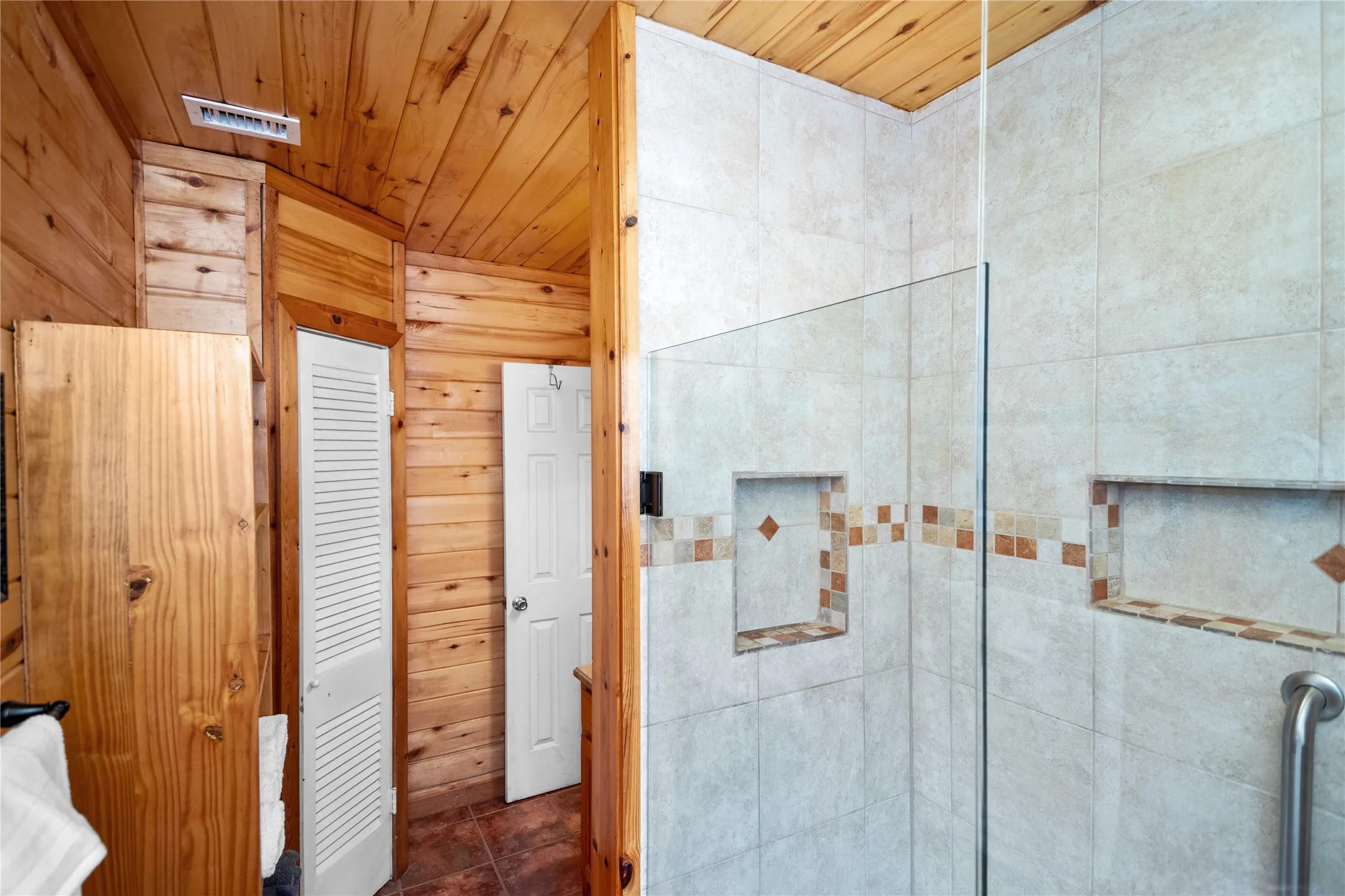 Bathroom with wood walls, tile floors, and wood ceiling