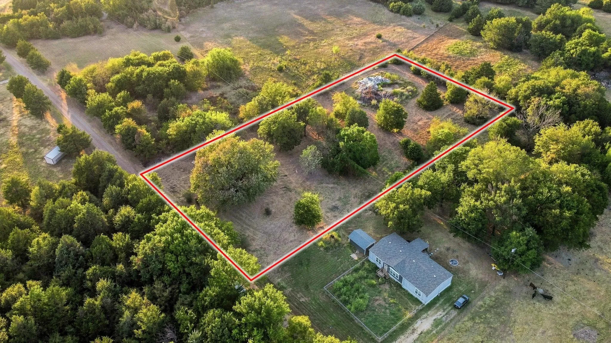 Expansive lot featuring mature trees and a single-story residence with a pitched roof