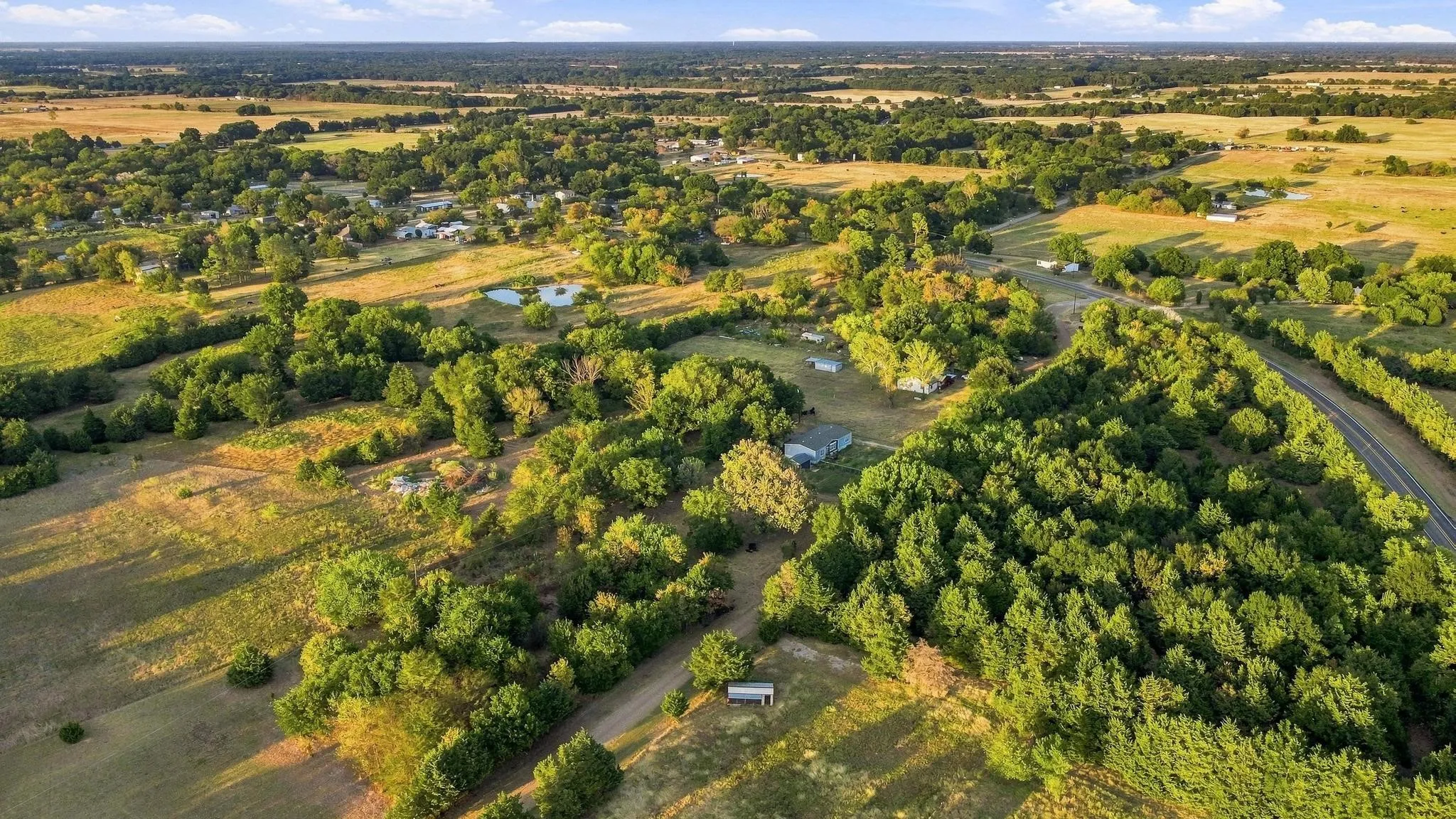 Expansive rural landscape with mature trees, open fields, and scattered structures