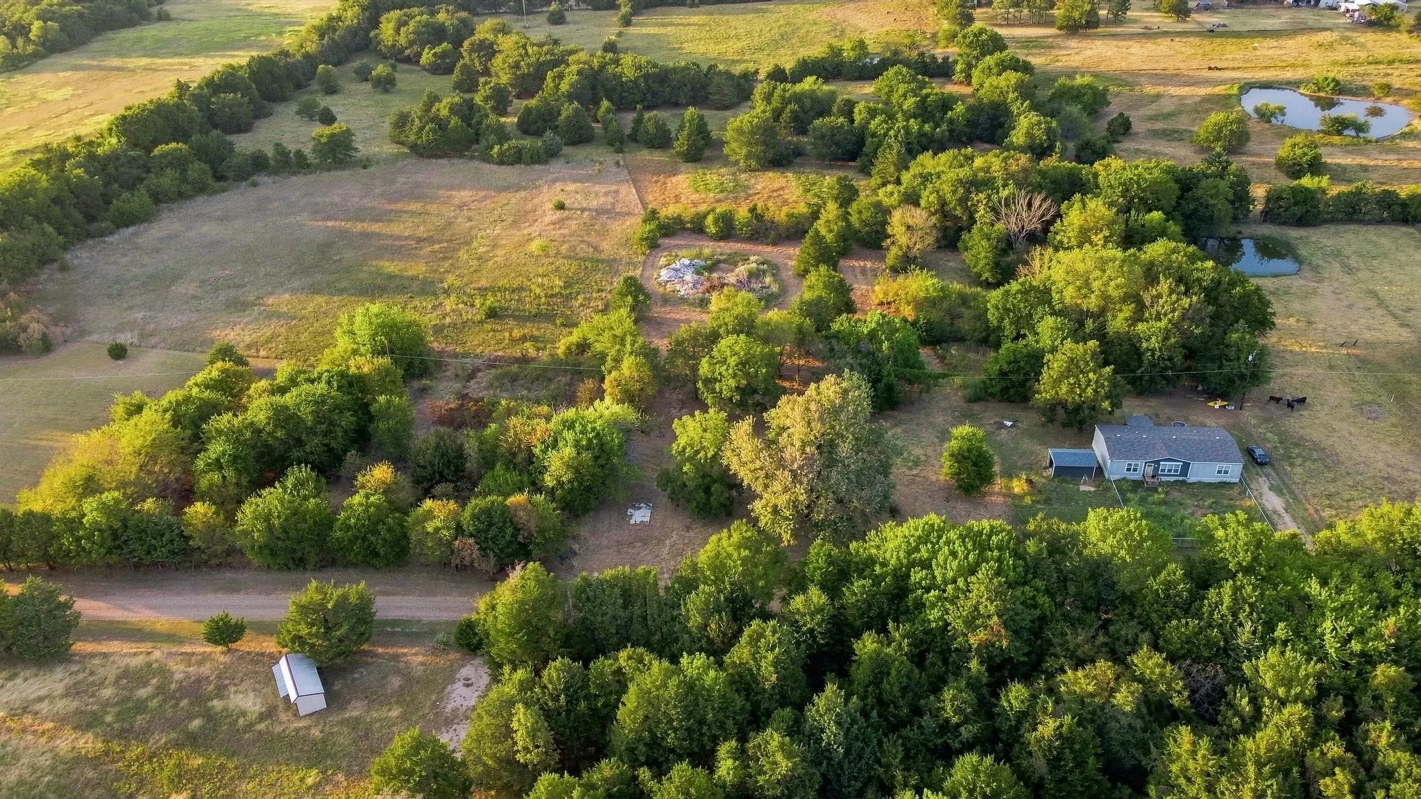 Expansive property featuring a single-story residence, surrounding mature trees, and multiple ponds