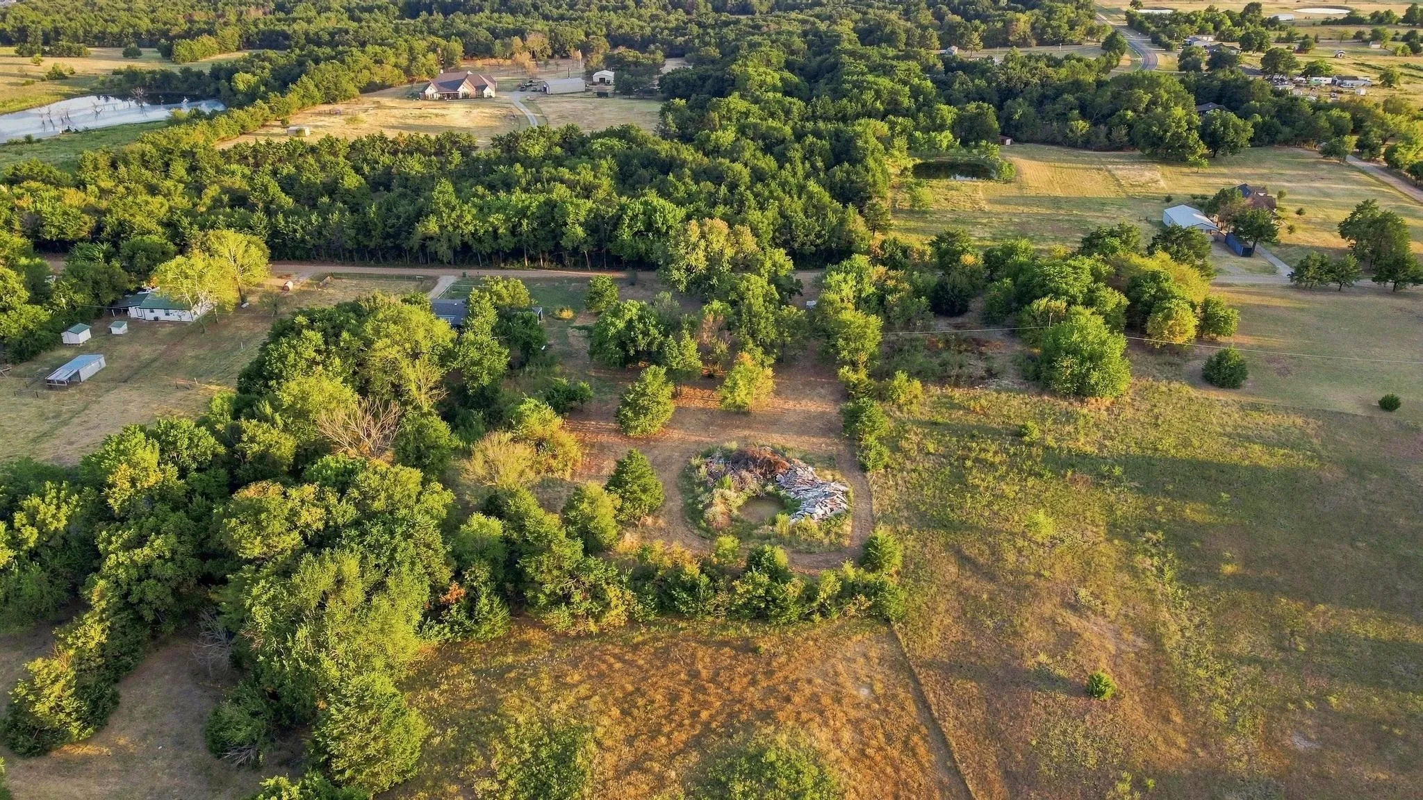 Expansive property featuring mature trees, open fields, and distant structures
