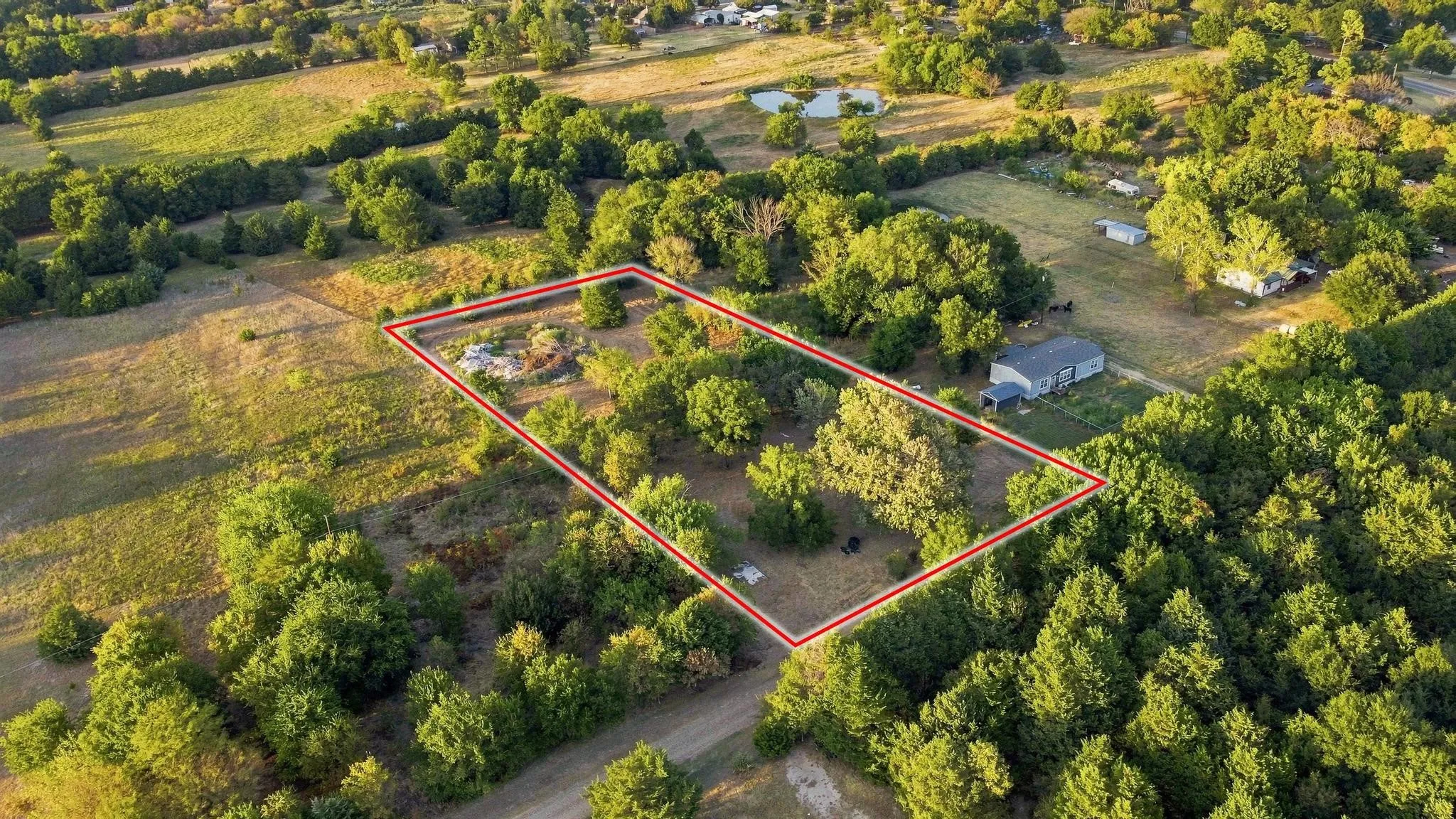 Expansive lot featuring mature trees and open land, bordered by additional green spaces