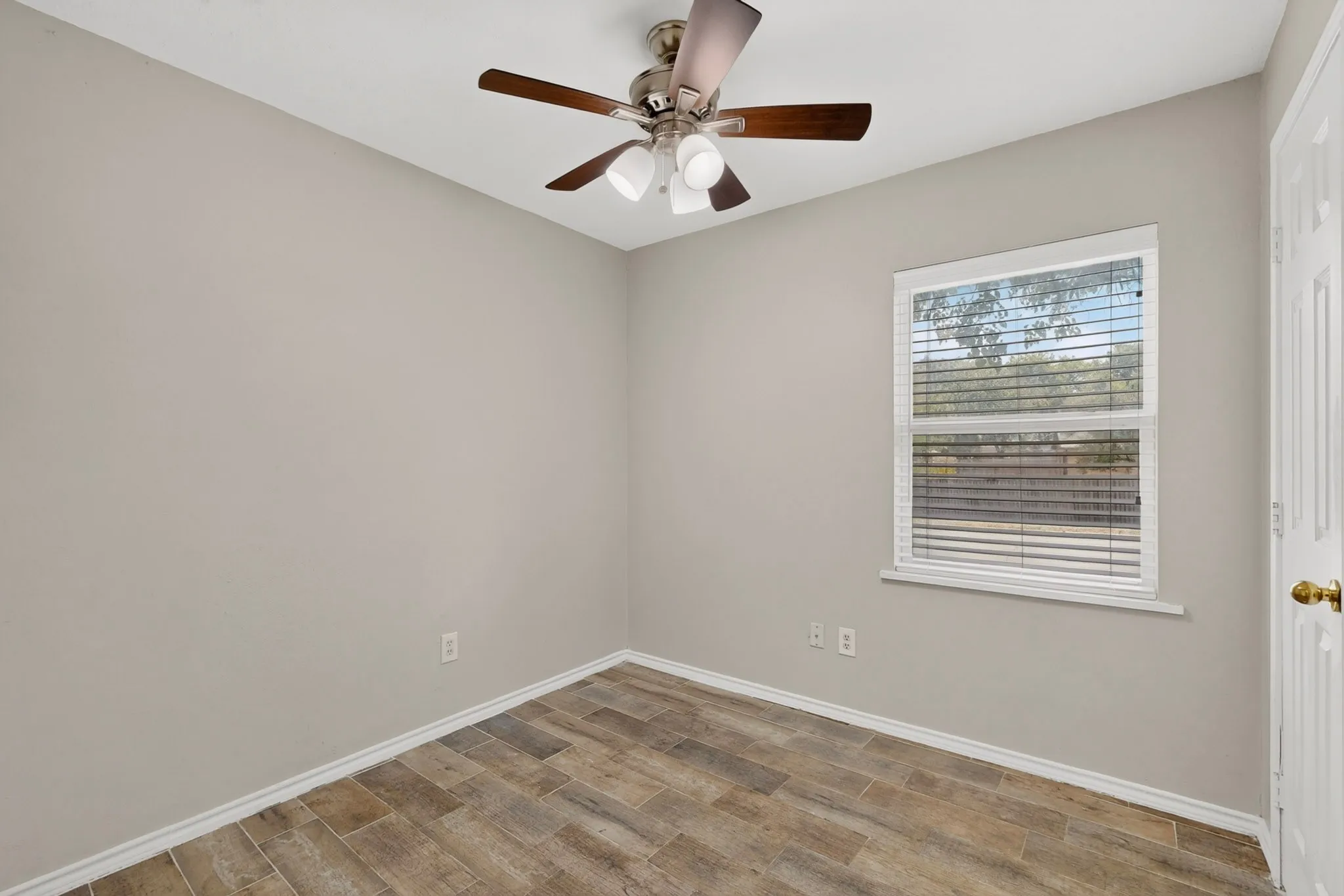 A cozy second bedroom featuring a ceiling fan and a window letting in natural light.