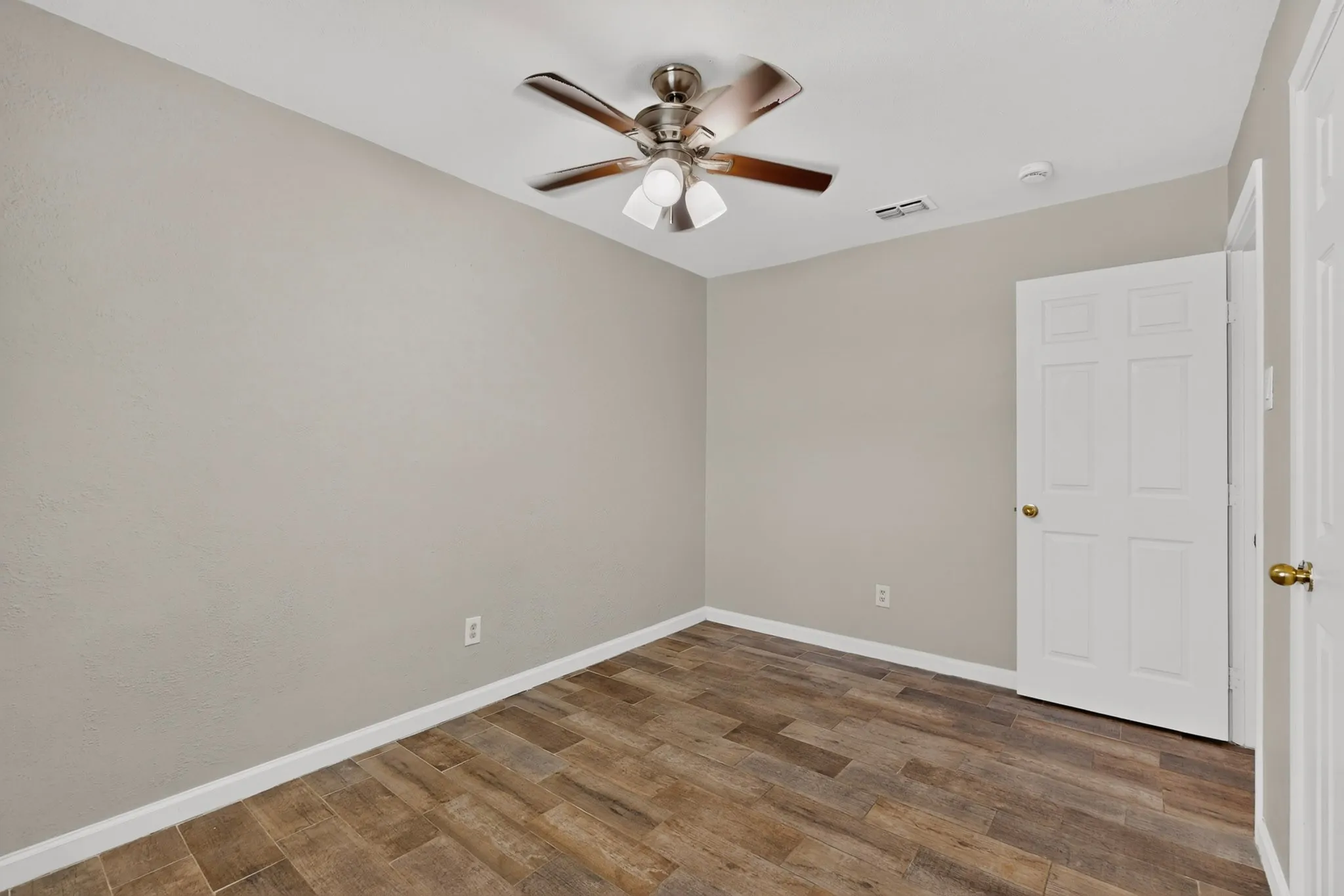 A cozy third bedroom with a ceiling fan, closet and hardwood floors.