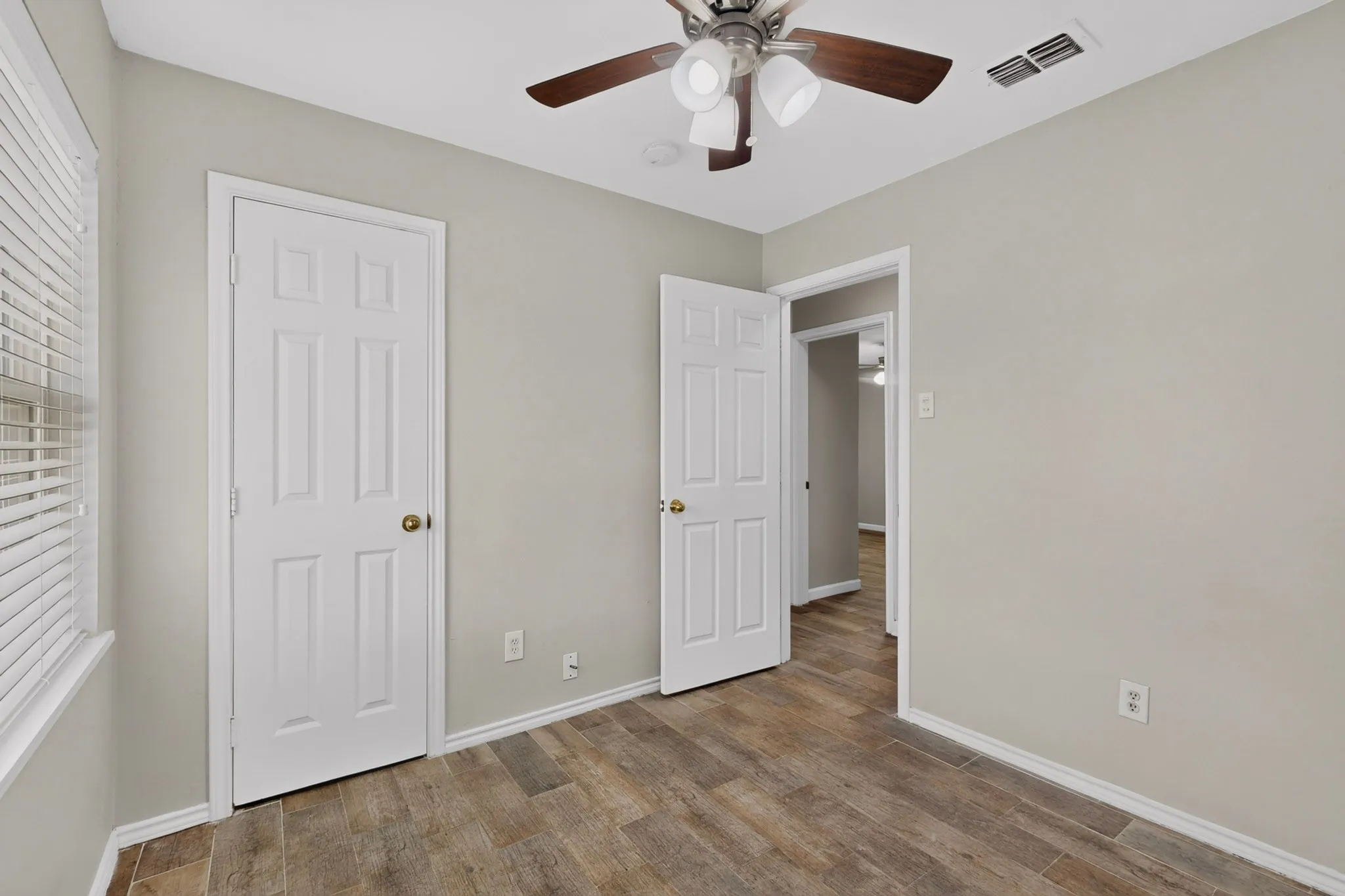 A cozy second bedroom featuring a ceiling fan, closet and a window letting in natural light.
