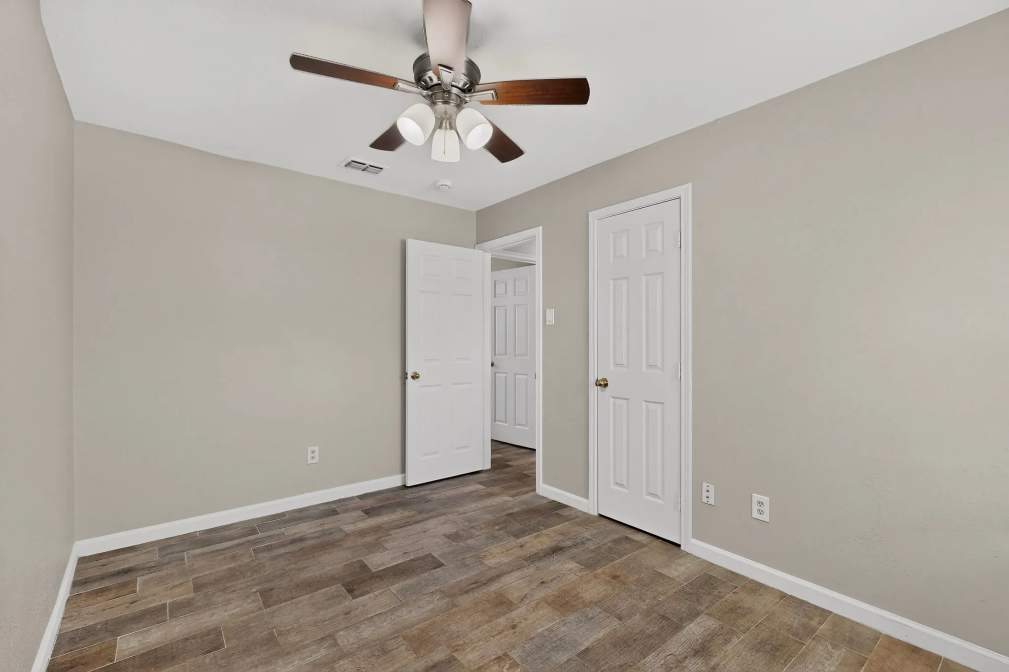 A cozy third bedroom with a ceiling fan and closet.