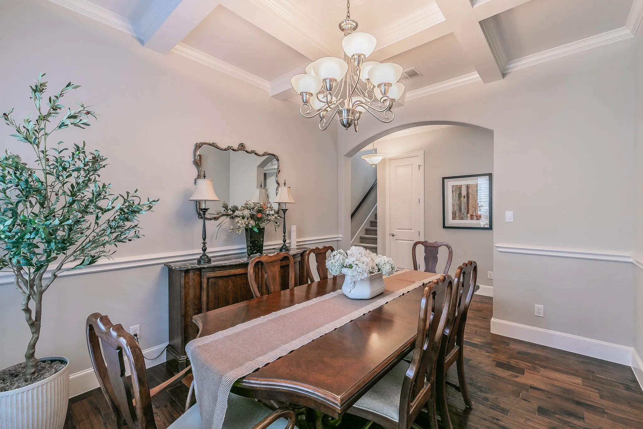 Coffered ceiling, decorative chandelier, wood flooring, and crown molding