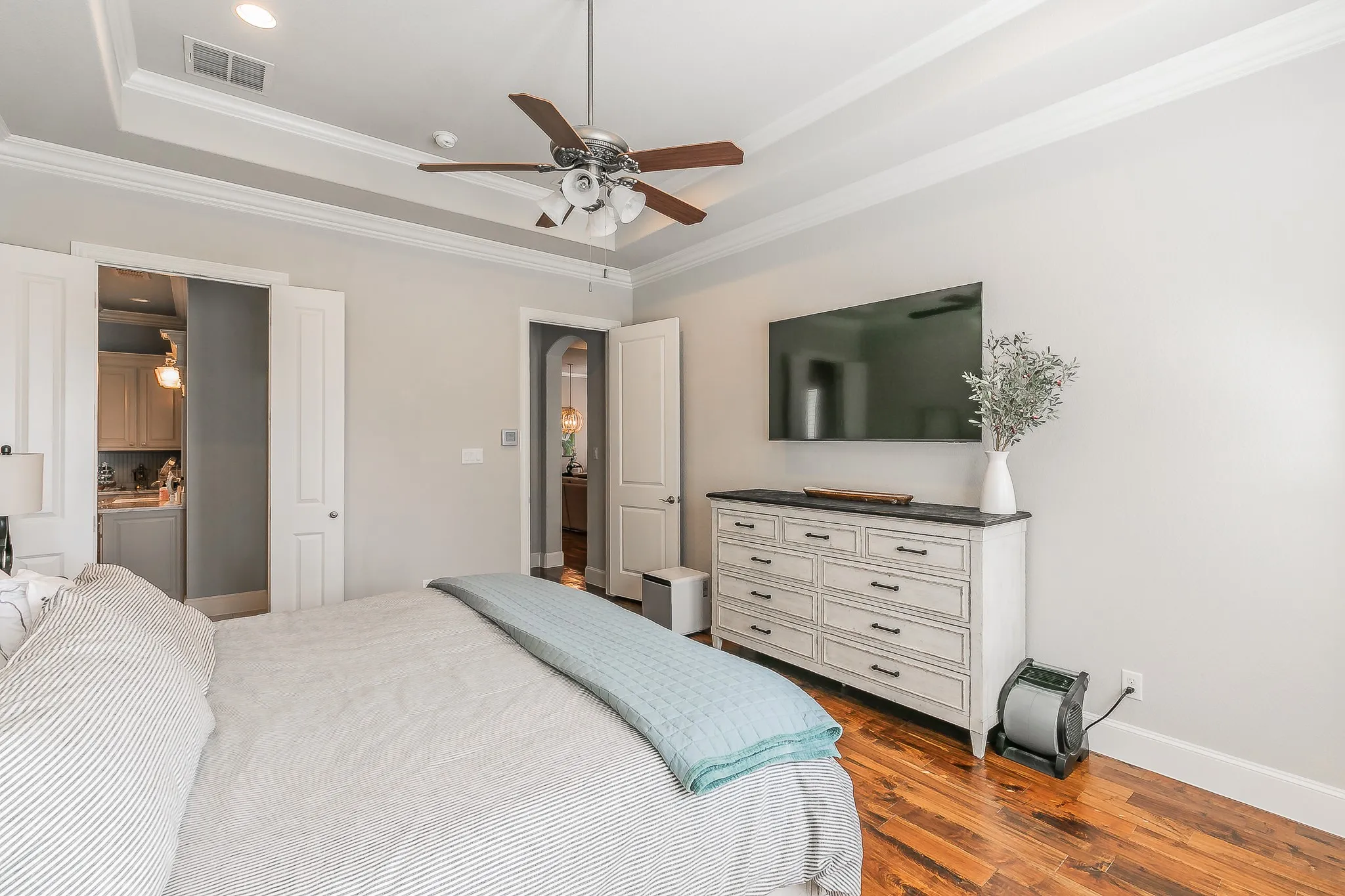 Tray ceiling with crown molding, ceiling fan with integrated lighting,  white paneled doors
