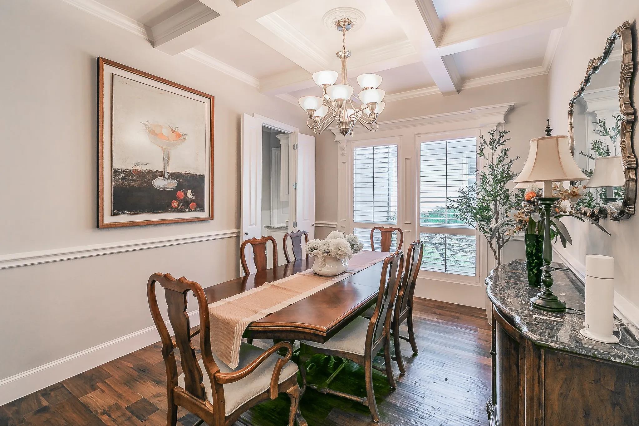 Tray ceiling with crown molding and a chandelier, hardwood flooring, dual windows with plantation shutters,