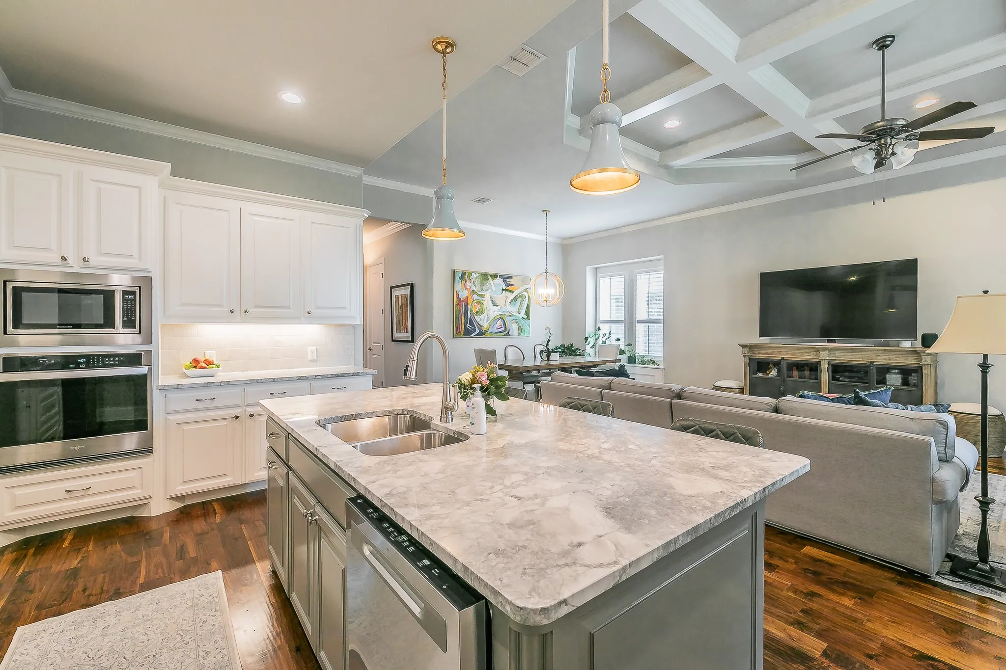 Kitchen featuring a large island with an undermount sink, stainless steel appliances, and white cabinetry