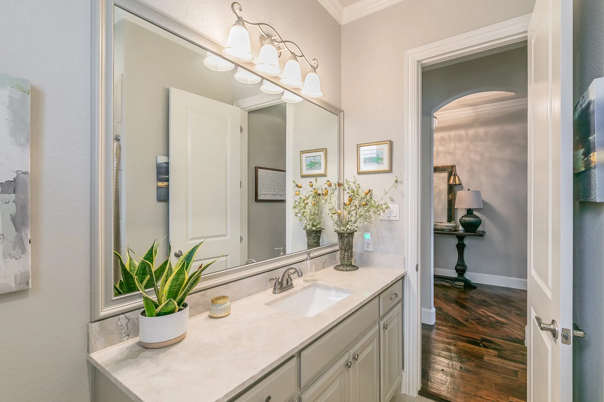 Vanity with an integrated sink and light-colored countertop, framed mirror, and a four-light vanity fixture