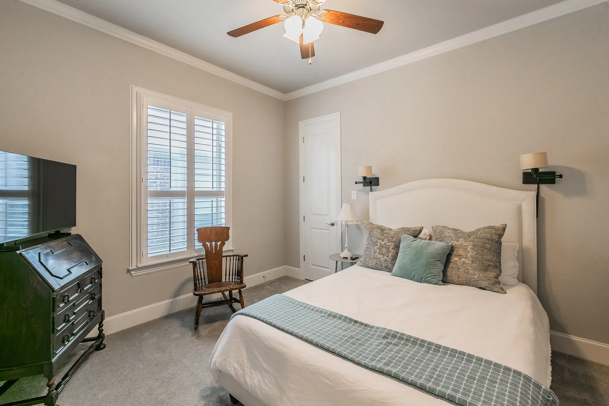 Recessed window with plantation shutters, ceiling fan with integrated lighting, and crown molding