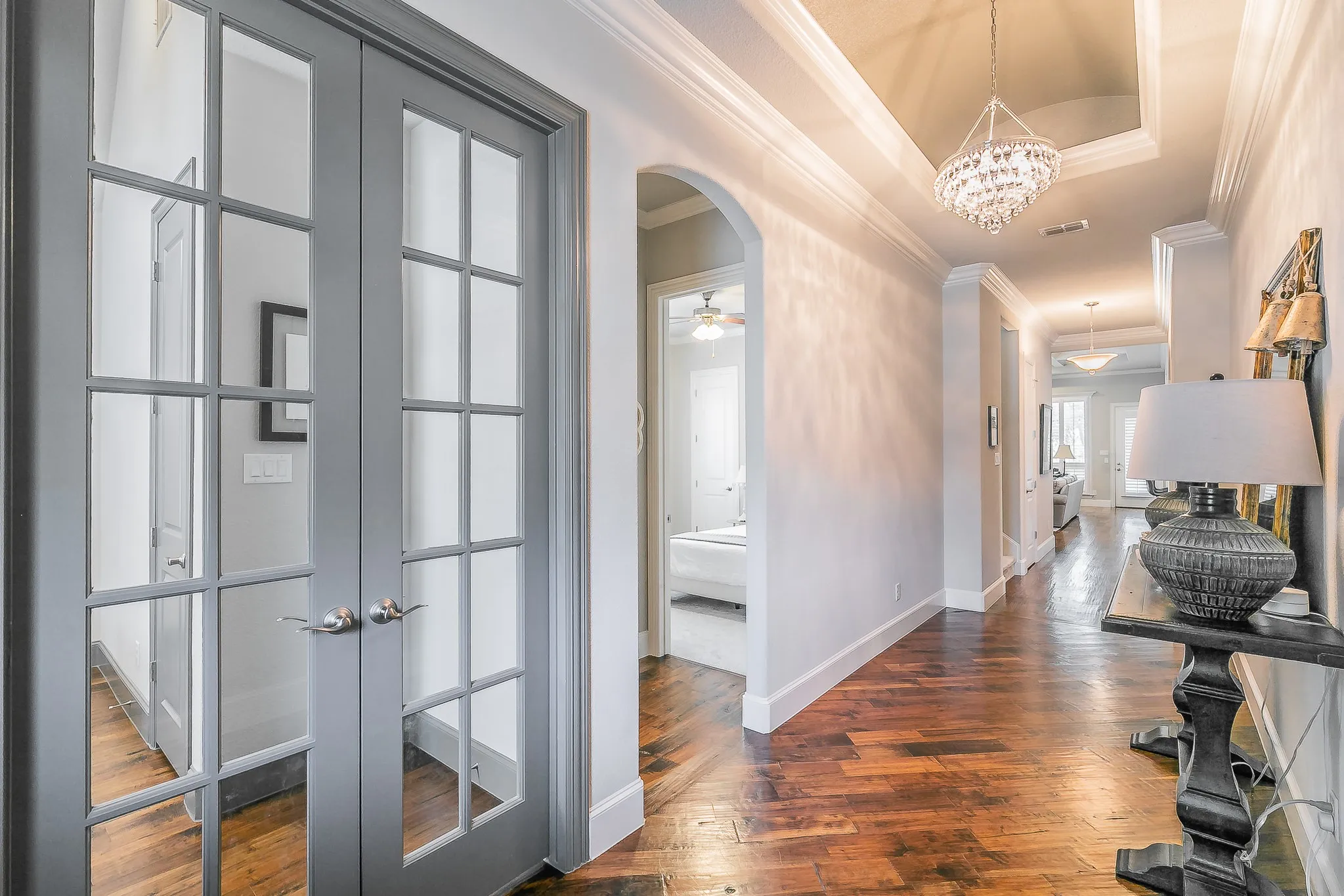 Tray ceiling with a crystal chandelier, wood flooring, and crown molding