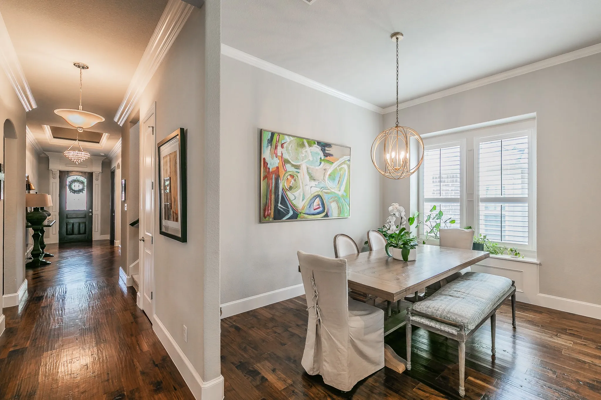 Hardwood flooring, crown molding, white window shutters, and a decorative chandelier