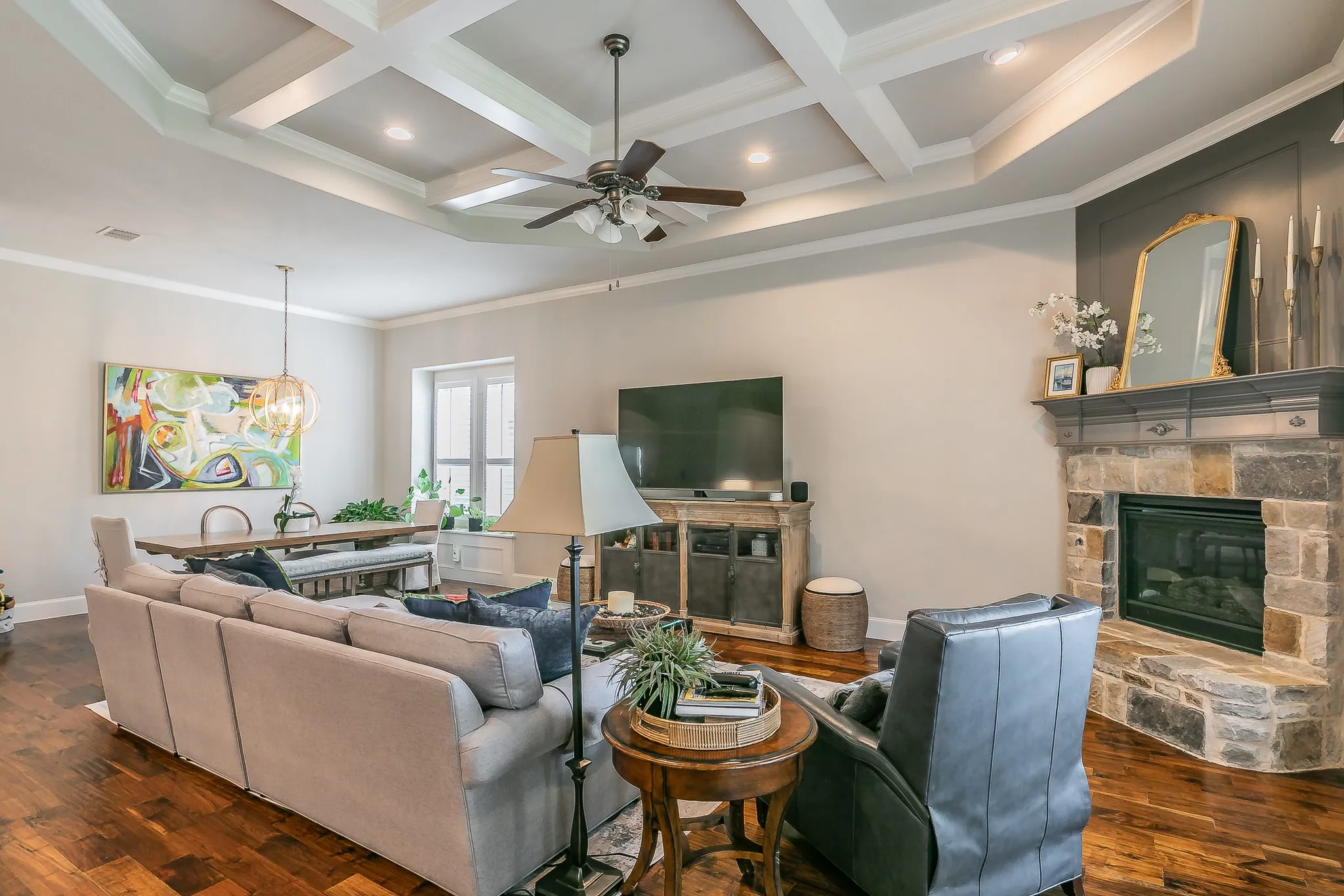 Coffered ceiling with recessed lighting, stone-clad fireplace with mantel, molding