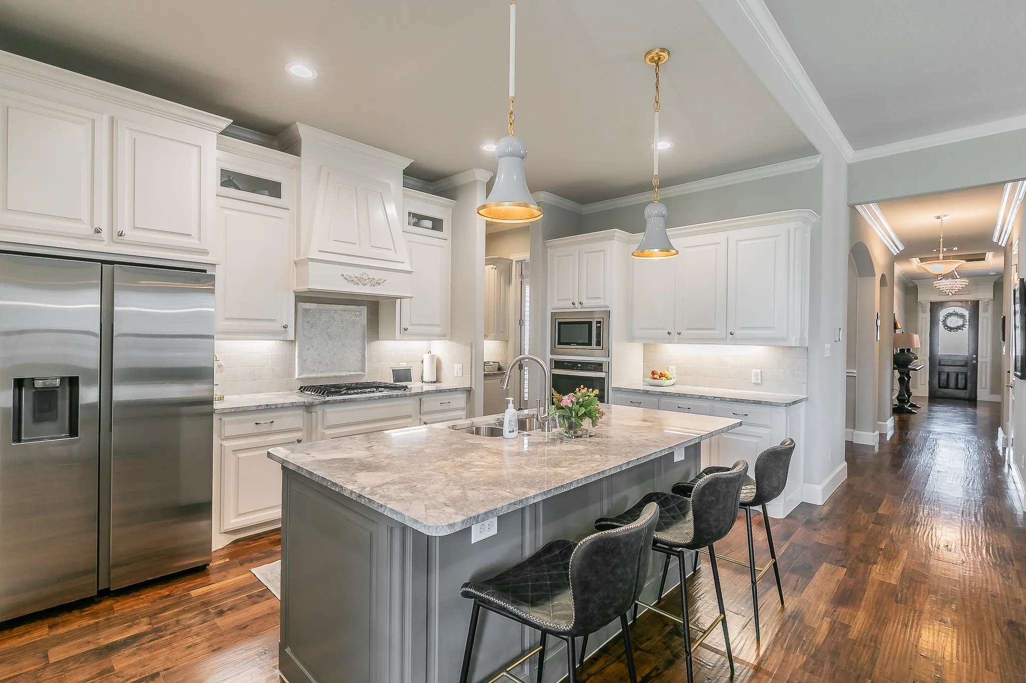 Gourmet kitchen featuring white cabinetry, stainless steel appliances, a large center island with seating