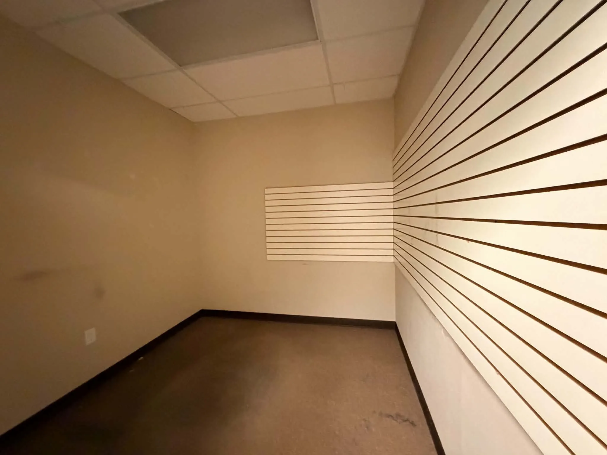 Commercial space featuring hard flooring, dropped ceiling, and slatwall panels