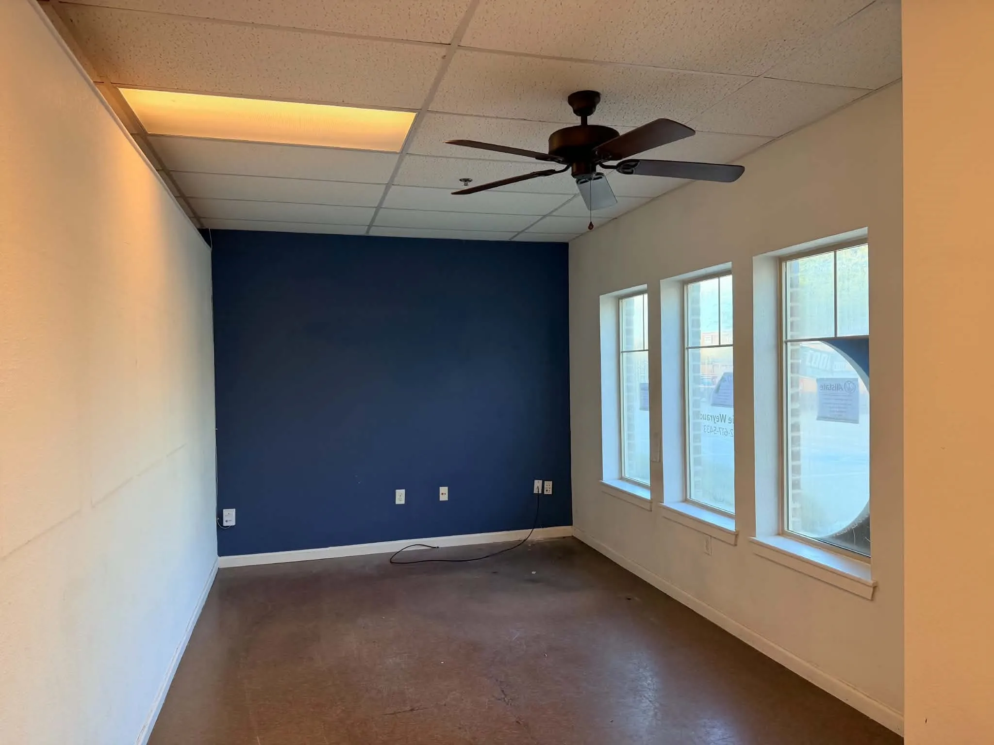 Recessed ceiling lighting, ceiling fan, three vertical windows, and a dark accent wall