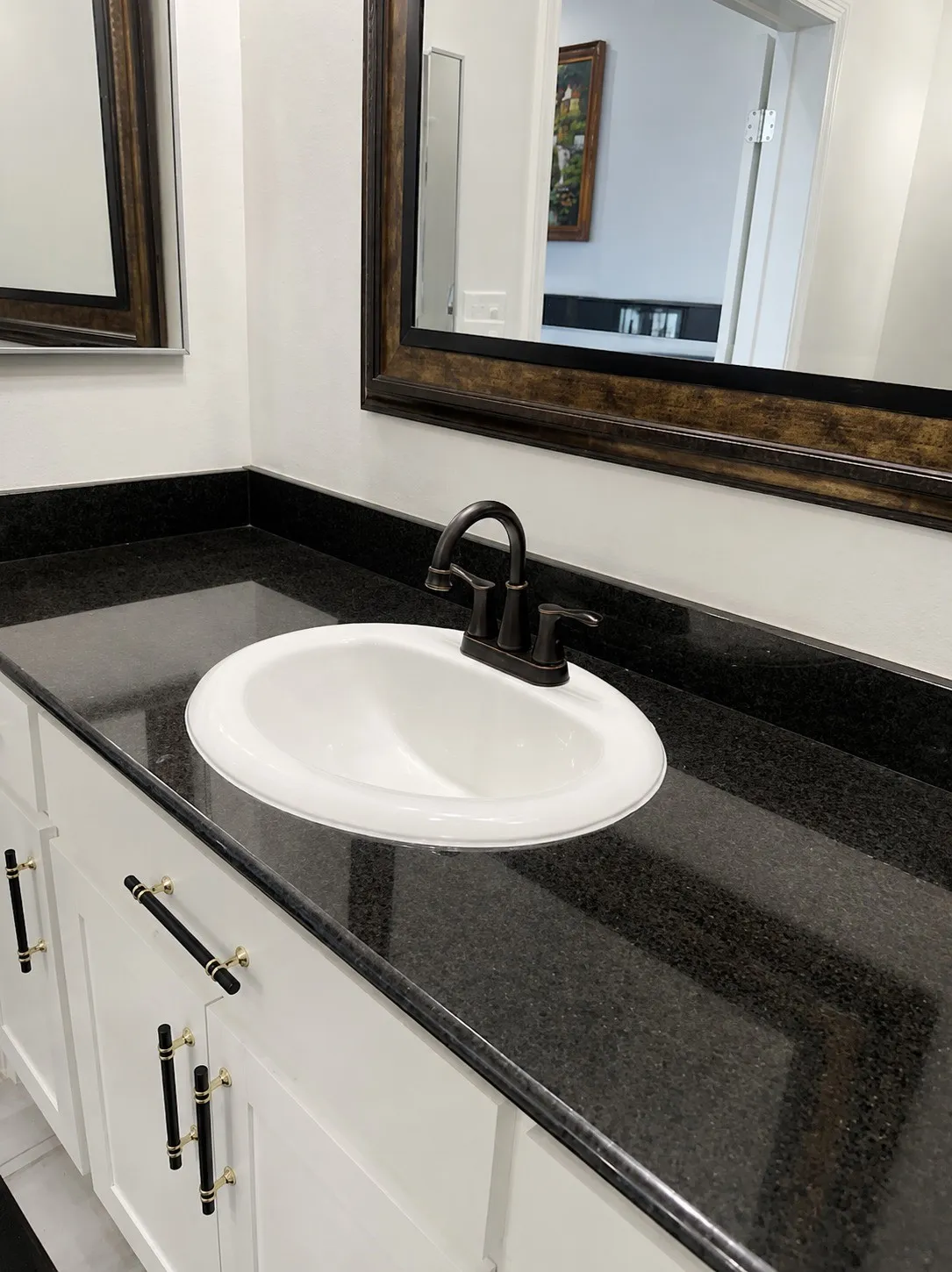 White vanity with dark stone countertop, undermount sink, and dark bronze faucet