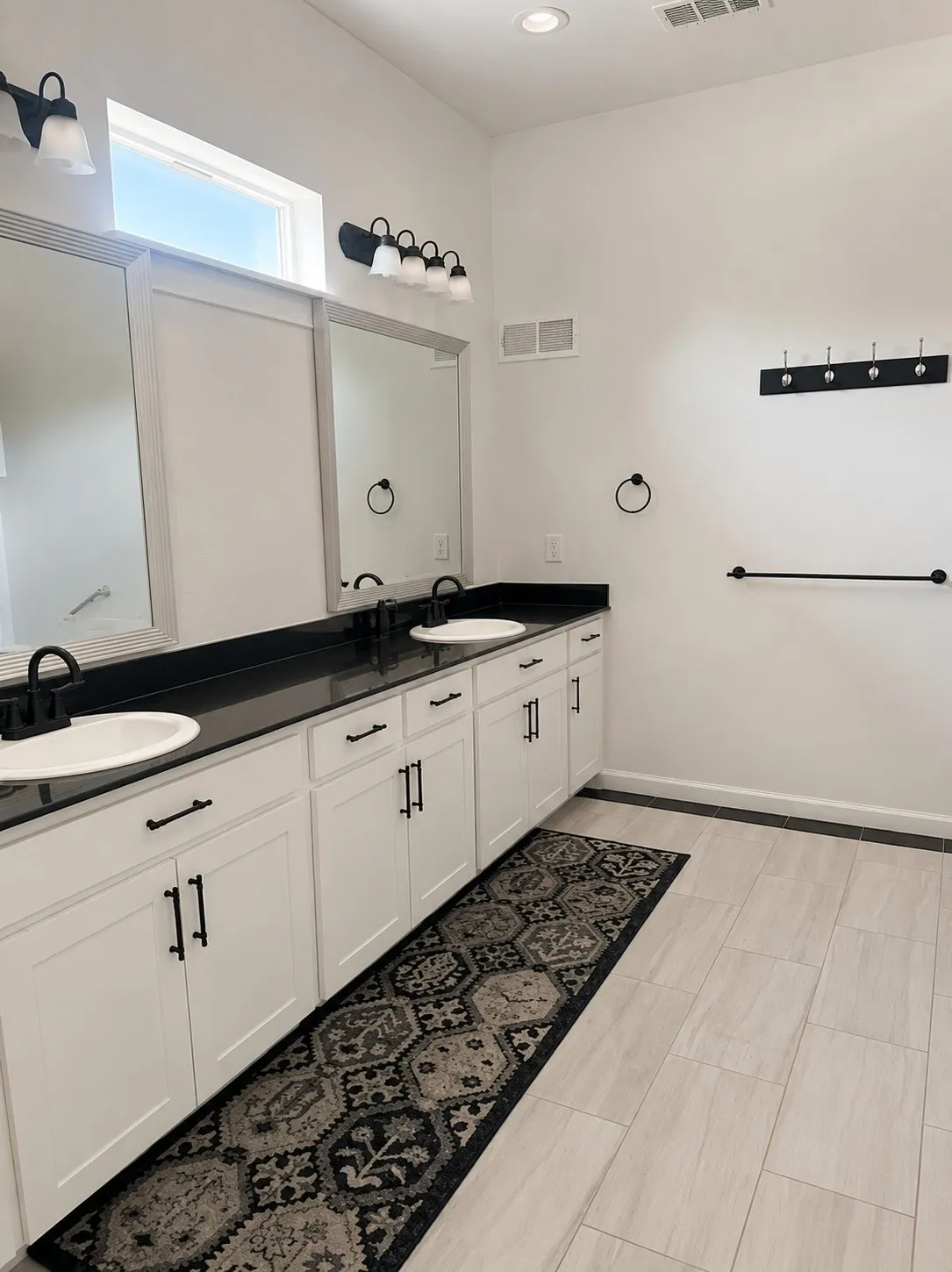 Dual vanity with dark countertops and white cabinetry, featuring two undermount sinks