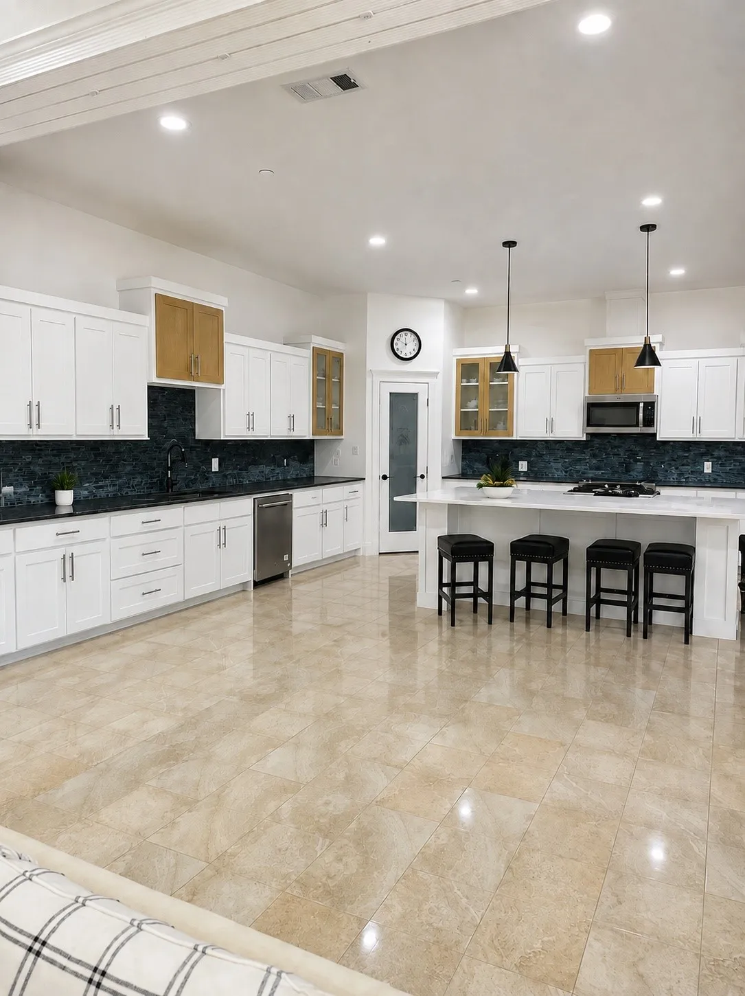 White cabinetry with gold-toned glass-front accents, dark tile backsplash, and light-toned tile flooring