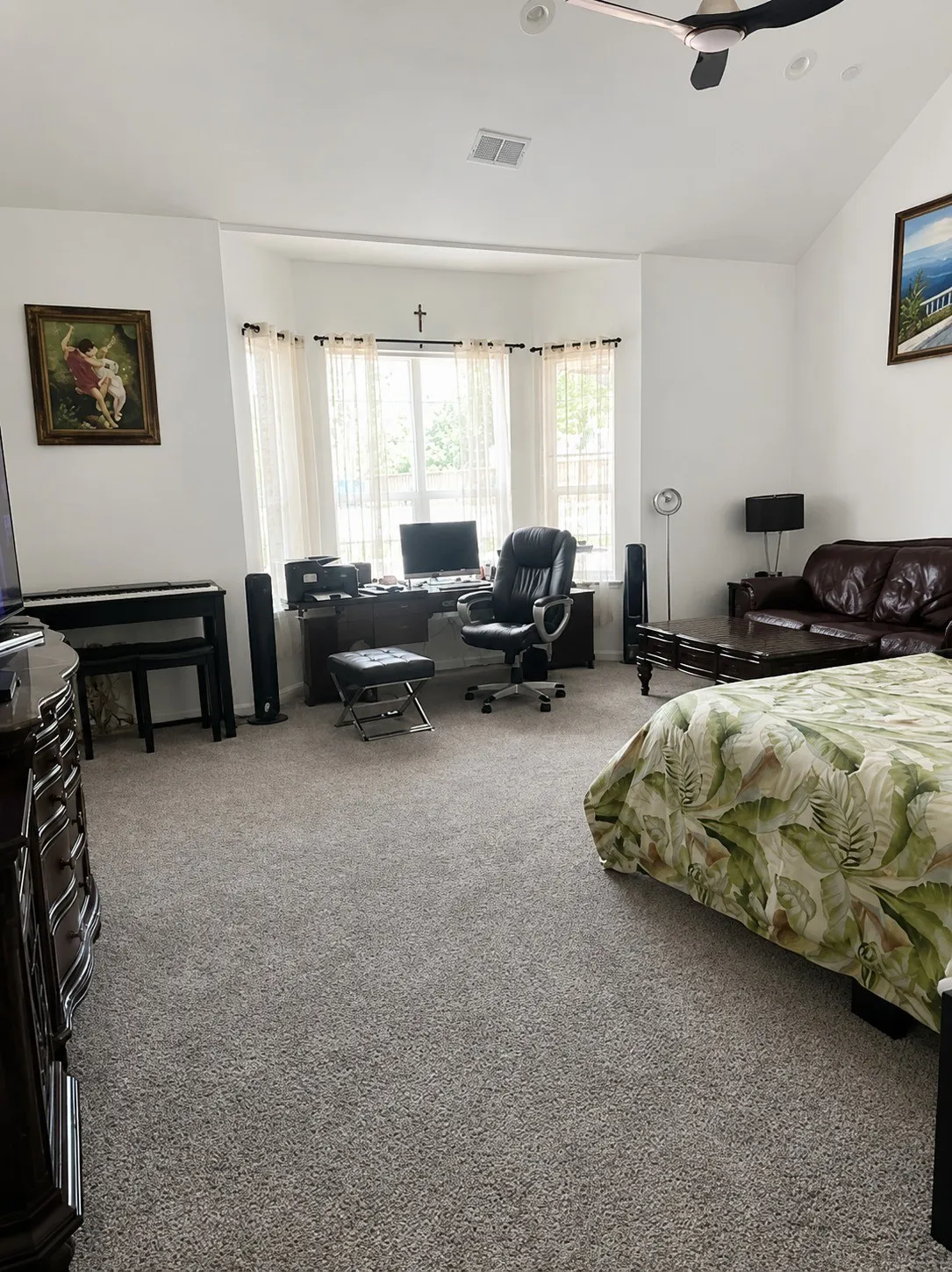 Vaulted ceiling, ceiling fan, bay window, light gray carpet, and white walls