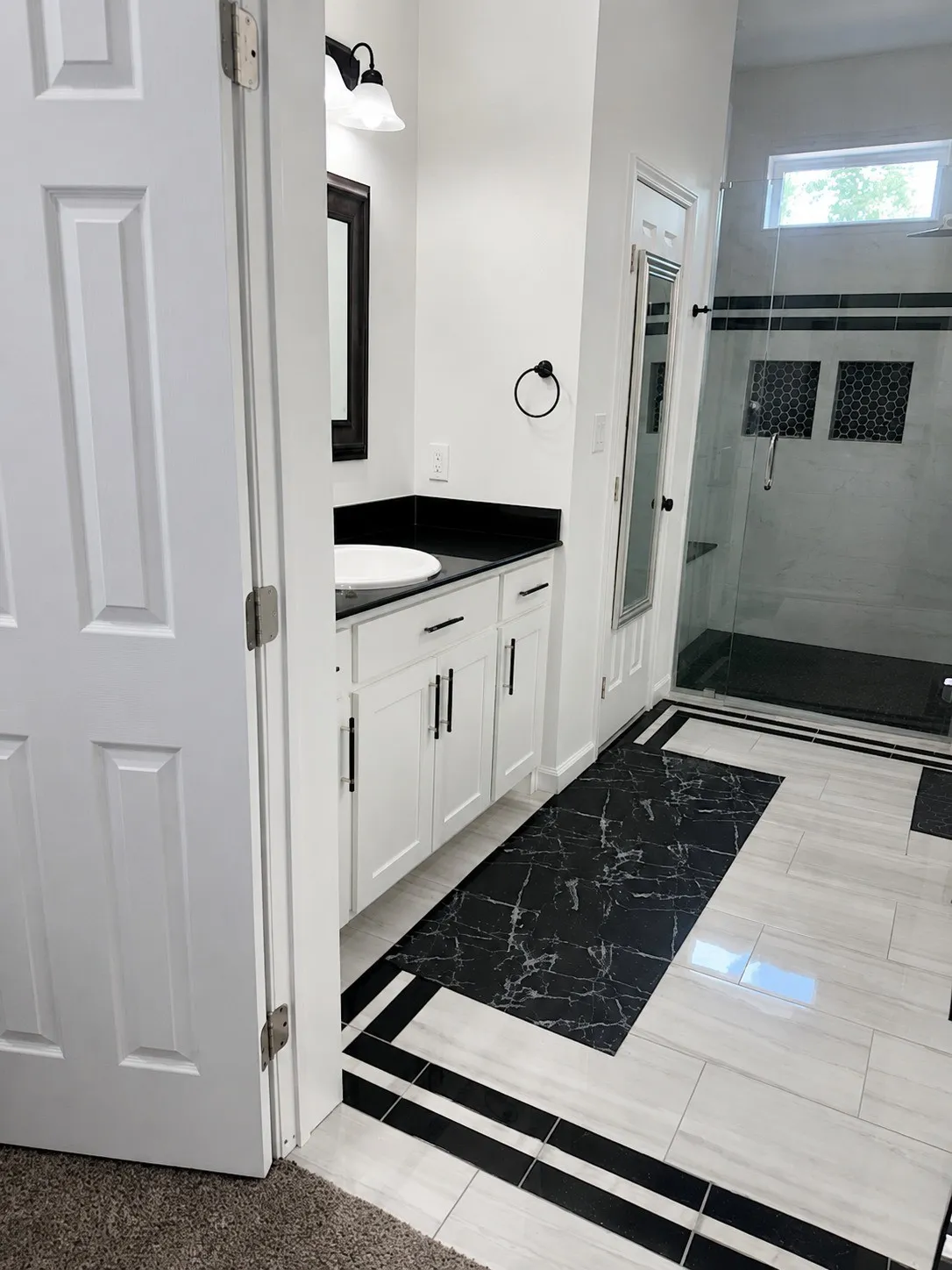 White shaker-style cabinetry with matte black hardware, dark stone countertop, vessel sink, and a walk-in shower with a glass enclosure