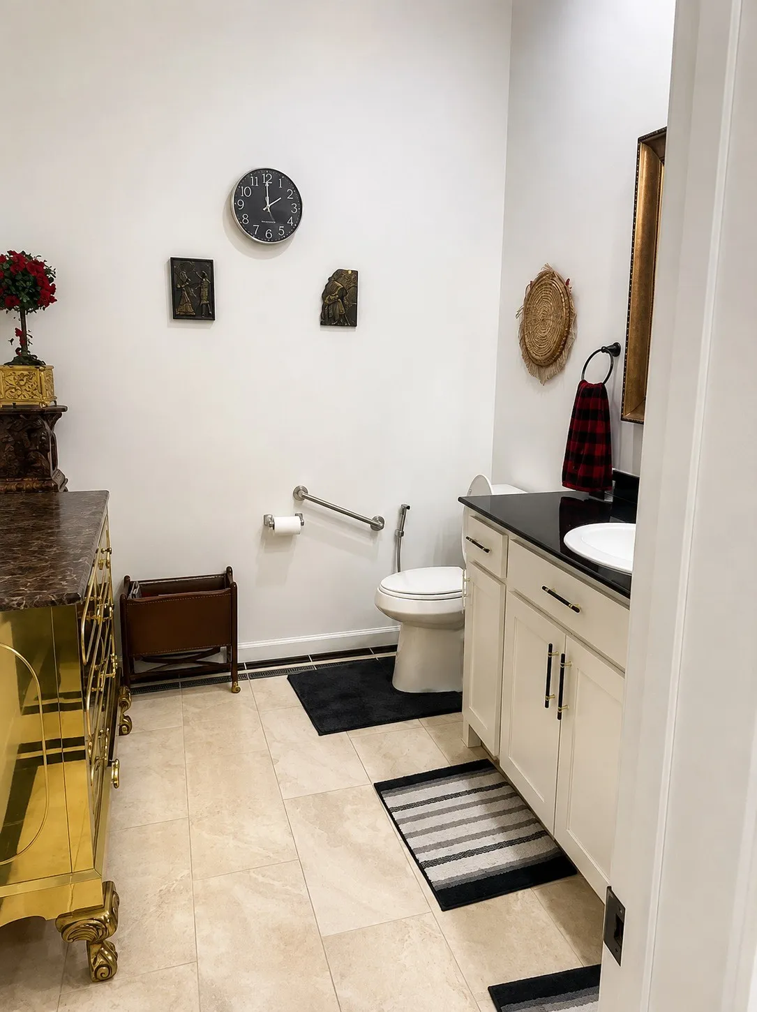 Light-colored tile flooring, white walls, built-in vanity with white cabinetry, black countertop, and a white basin sink