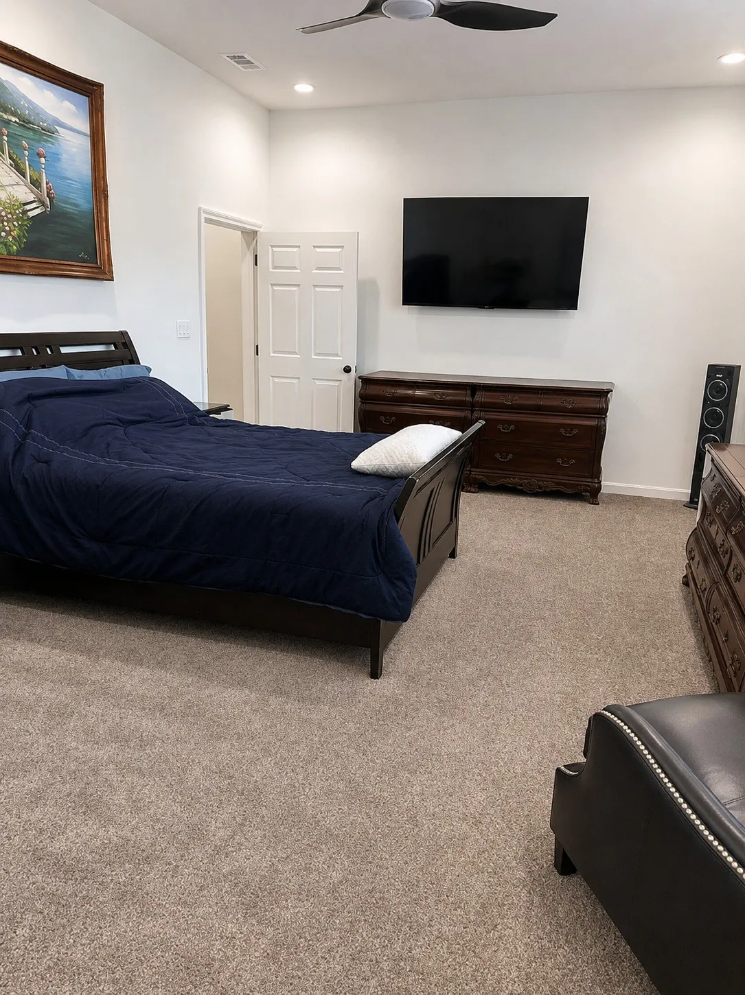 Recessed ceiling lighting, ceiling fan, neutral wall paint, and light-colored carpeting