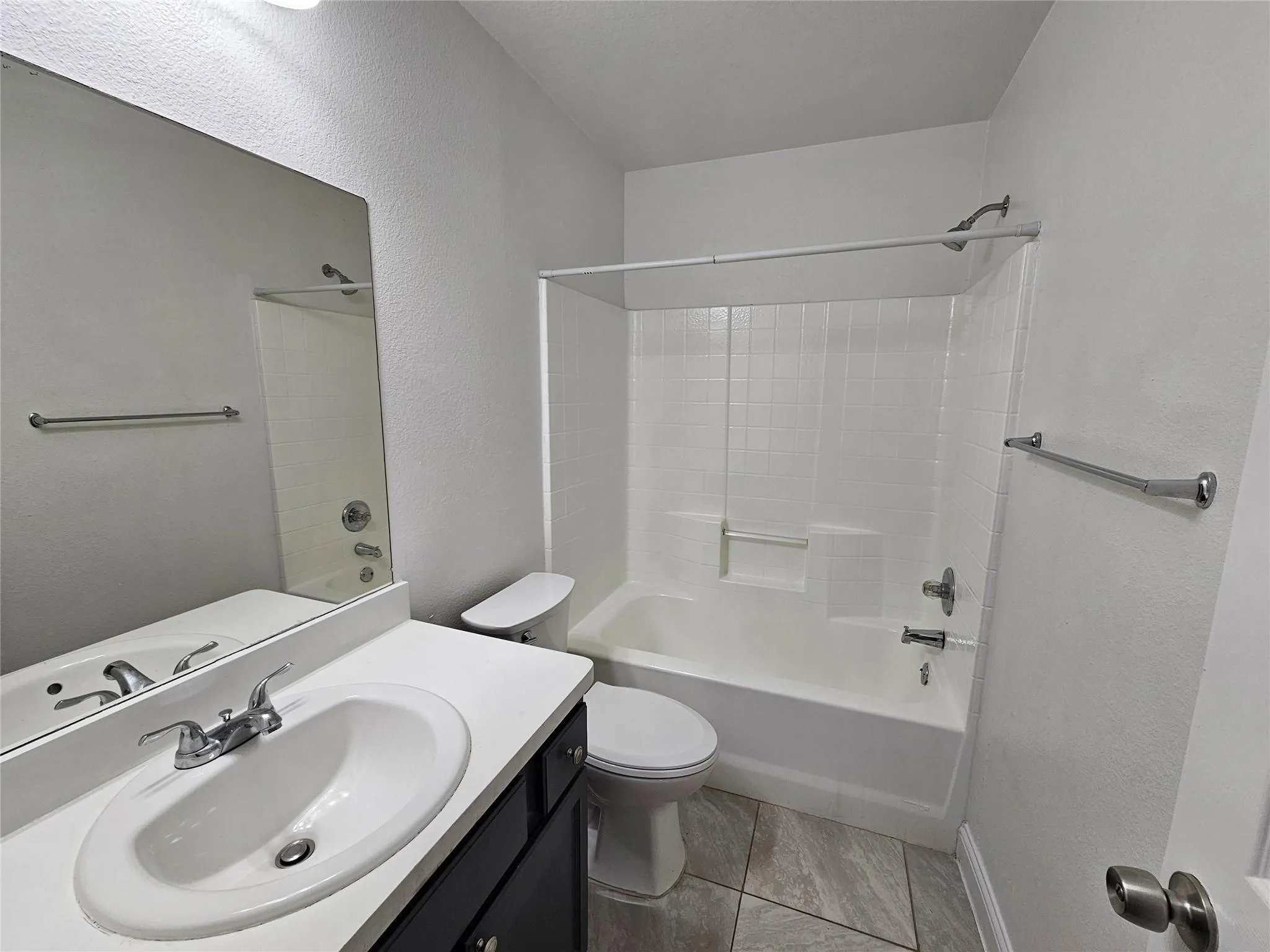 Bathroom with a vanity, oval sink, and a combination tub and shower with white tile surround