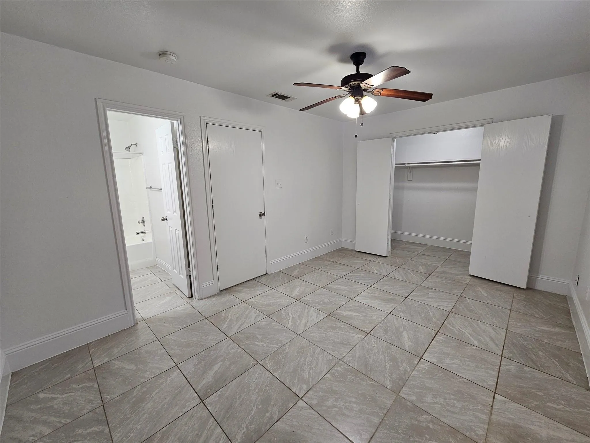 Tiled flooring throughout, ceiling fan with integrated lighting, and a closet with bi-fold doors