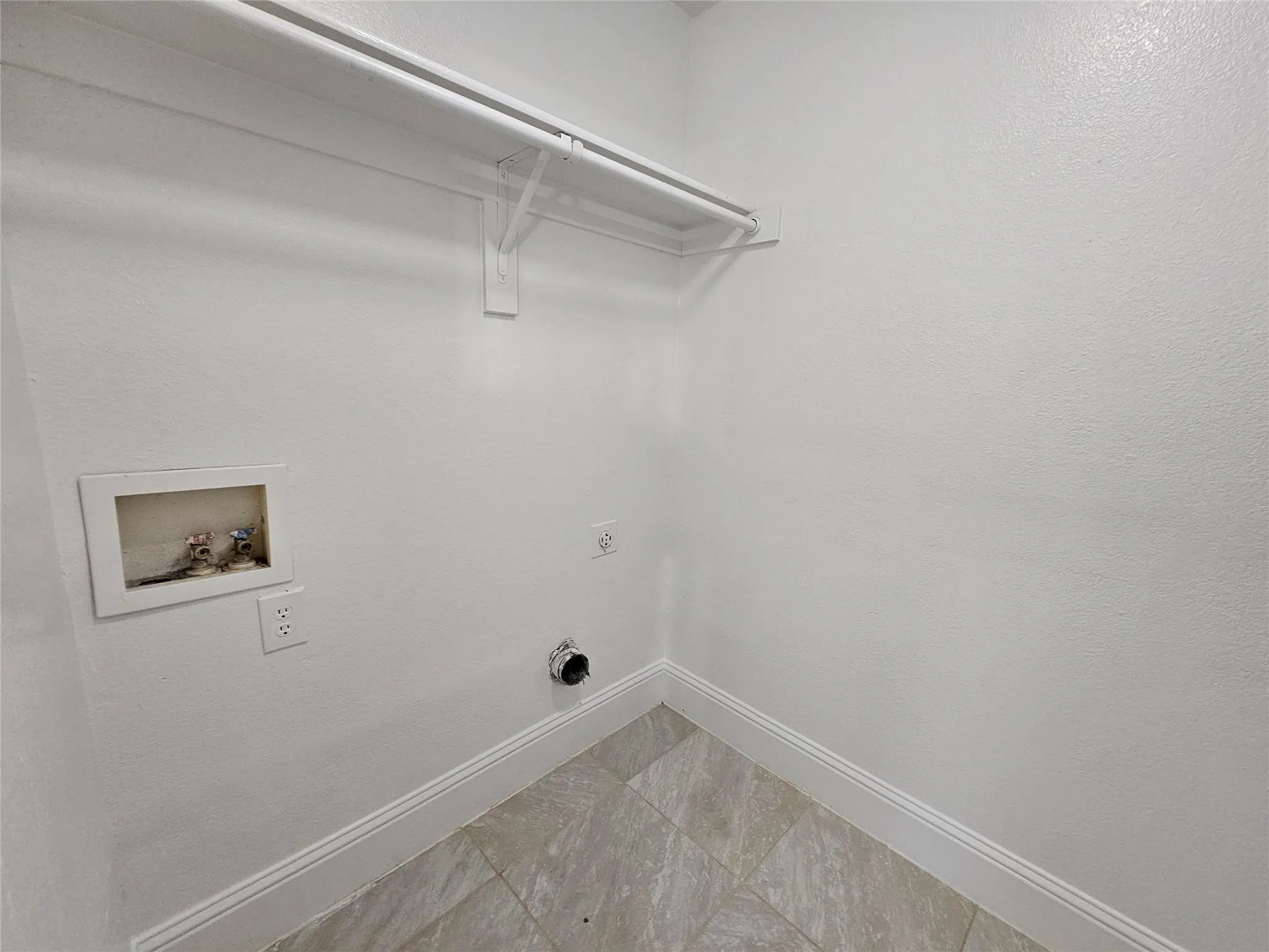 Laundry utility area with tile flooring and a wall-mounted clothing rod
